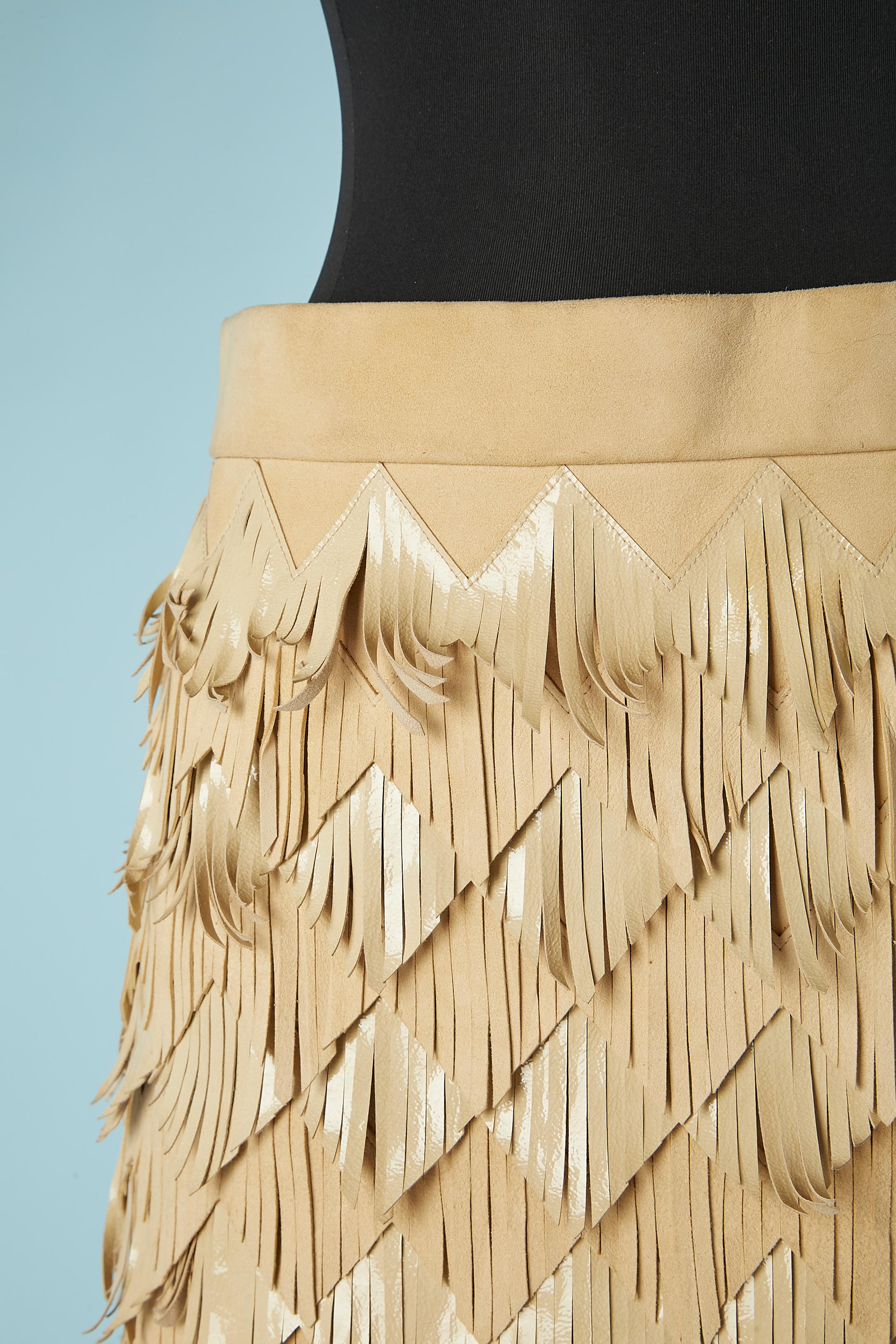 Beige skirt with fringes in suede and patent leather. Silk organza branded lining. Zip on the left side with hook&eye. Show prototype. Lenght including fringes= 95 cm. Lenght of the mini skirt underneath= 40 cm 
Collection Métiers d'Art Paris Dallas