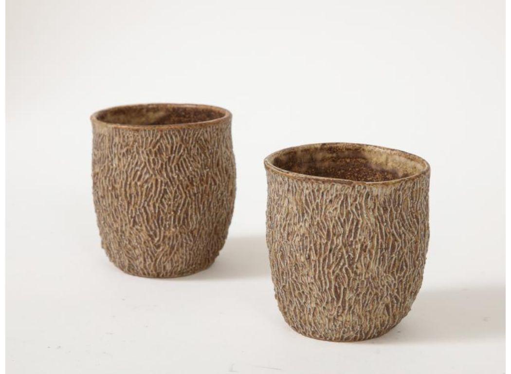 Small cups with expressive, hand-sculpted texture. 

