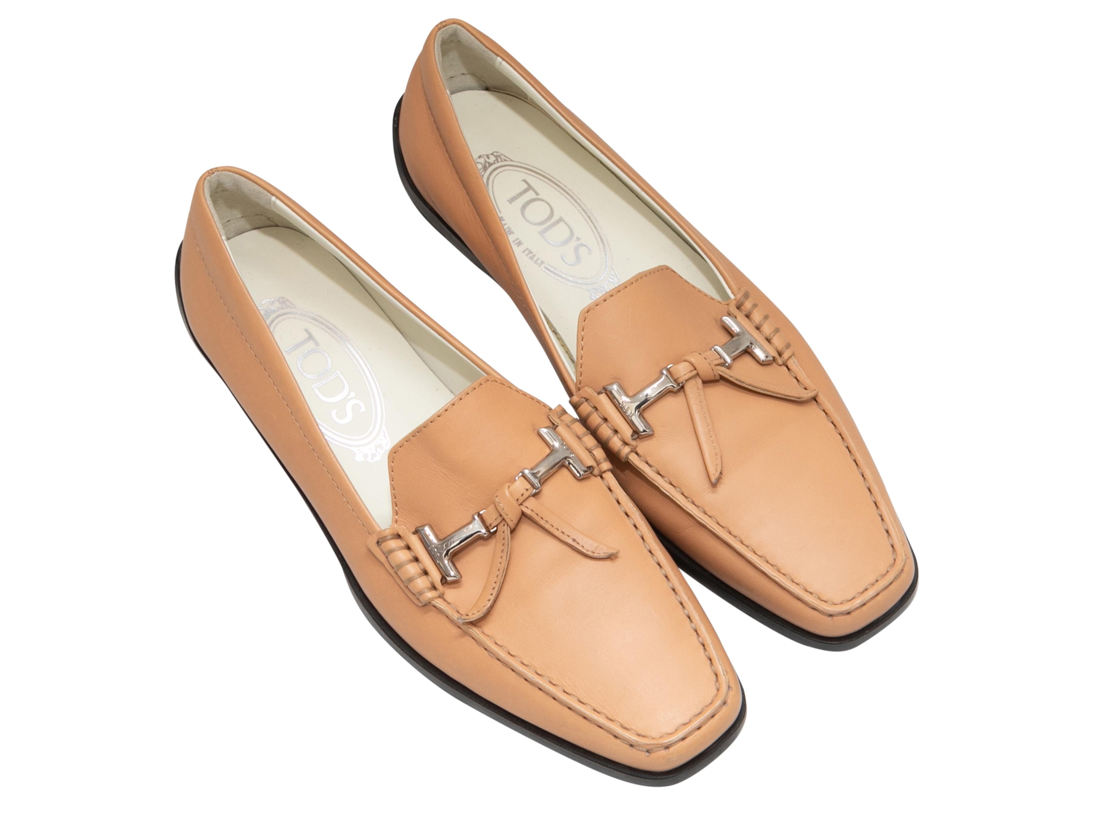 Mocassins en cuir beige de Tod's. Détails en métal argenté sur le dessus. Pare-chocs en caoutchouc au niveau des contreforts et des semelles. Hauteur du talon de 0,75