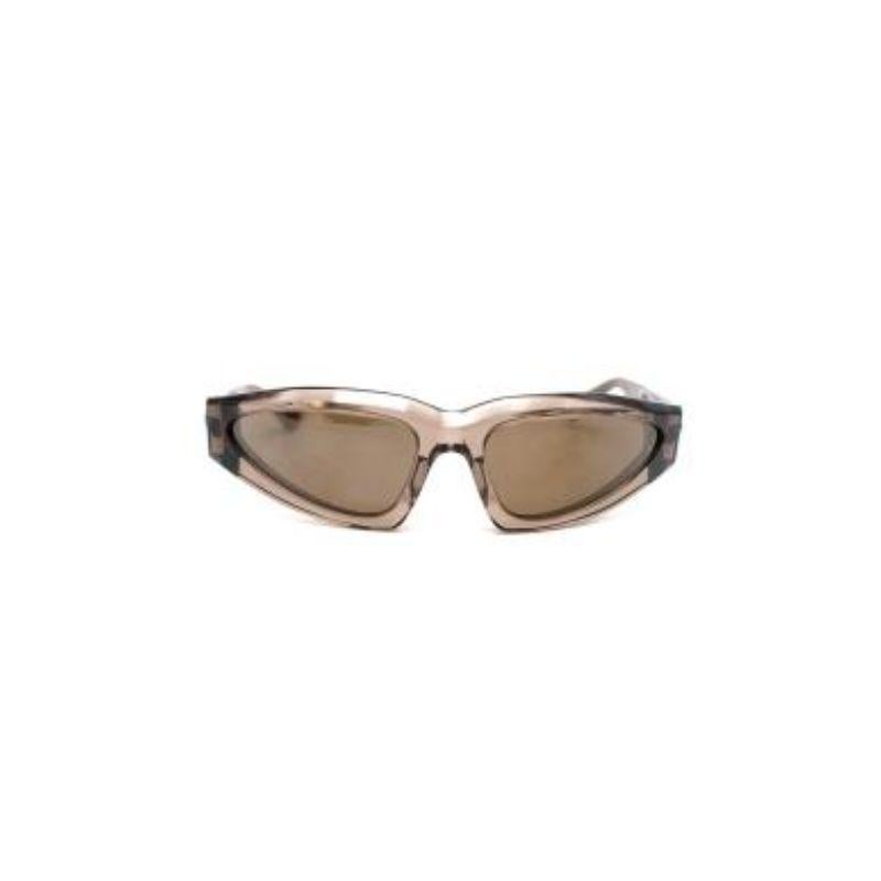 Bottega Veneta beigefarbene durchscheinende Acetat-Sonnenbrille
 
 - Klarer, beige getönter eckiger Rahmen 
 - Moderne Katzenaugen-Silhouette
 - Getönte Gläser 
 - Zweifarbige Verzierungen an den Armen
 - Dezentes Branding 
 
 Materialien
 Acetat
 
