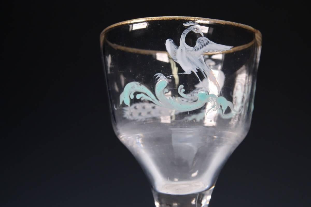 Una excepcionalmente rara y exquisita copa de vino esmaltada Beilby de giro opaco hacia 1765.
El generoso cuenco conopial está esmaltado en el más fino blanco con un pavo real y una pava real, cada uno de ellos posado sobre volutas rococó turquesas