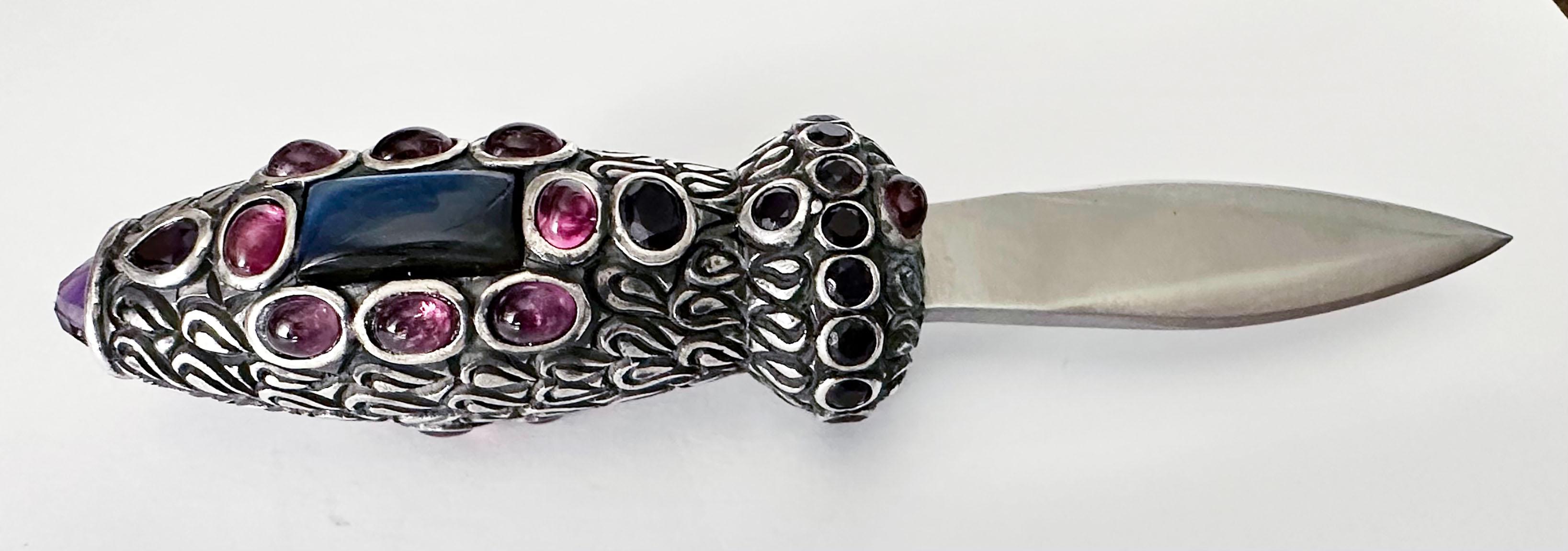 This stunning letter opener is a must-have addition to any desk or collection. The handle is crafted from high-quality silver and adorned with beautiful amethyst, rubellite, and labradorite stones. The unique design and exquisite details make this