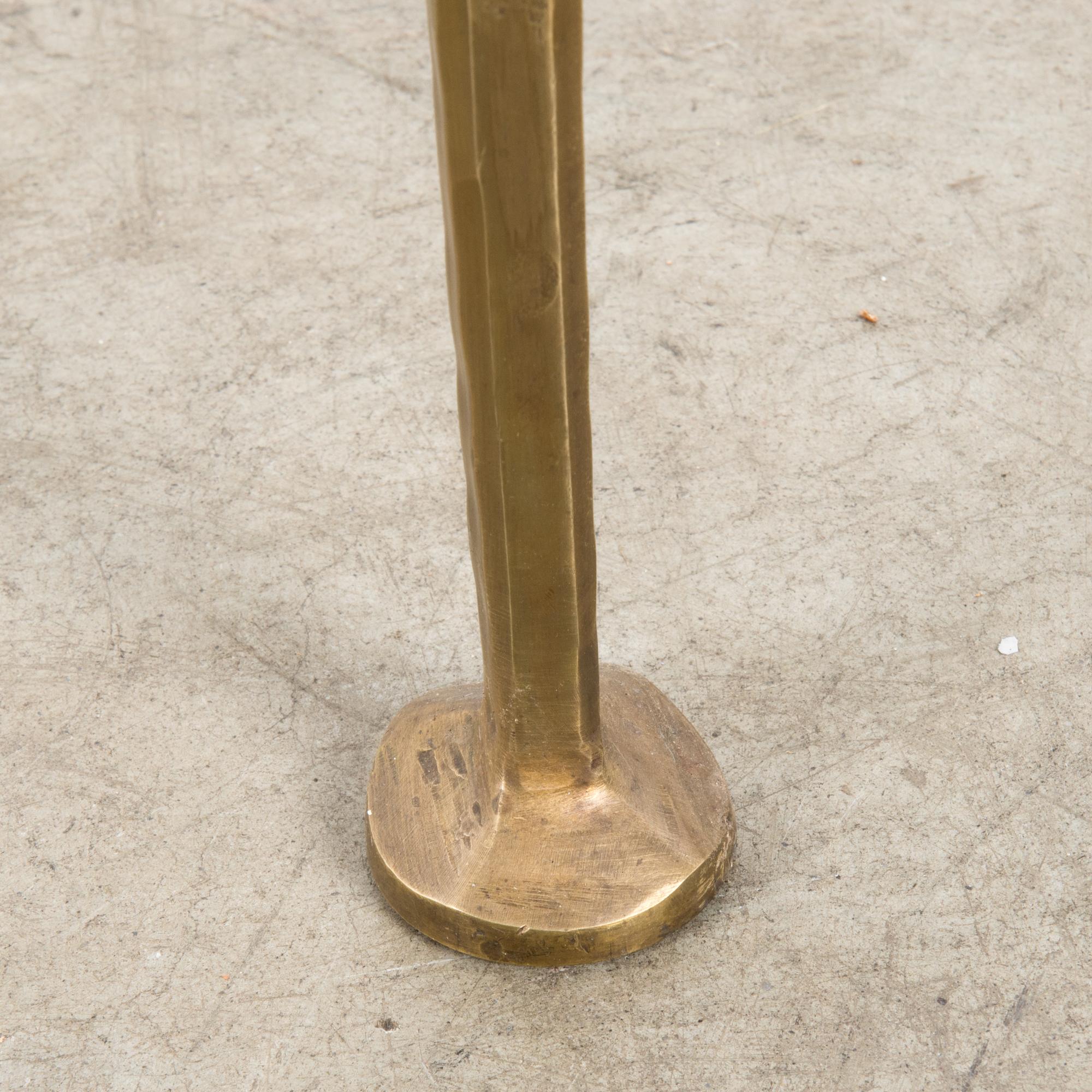 A brass table from Italy, circa 1970, with a glass top. A three-cornered shape, with an impression of weight and sophistication. The brass of the frame is forged into expressive contours, at once angular and fluid. The legs have a telescopic taper.