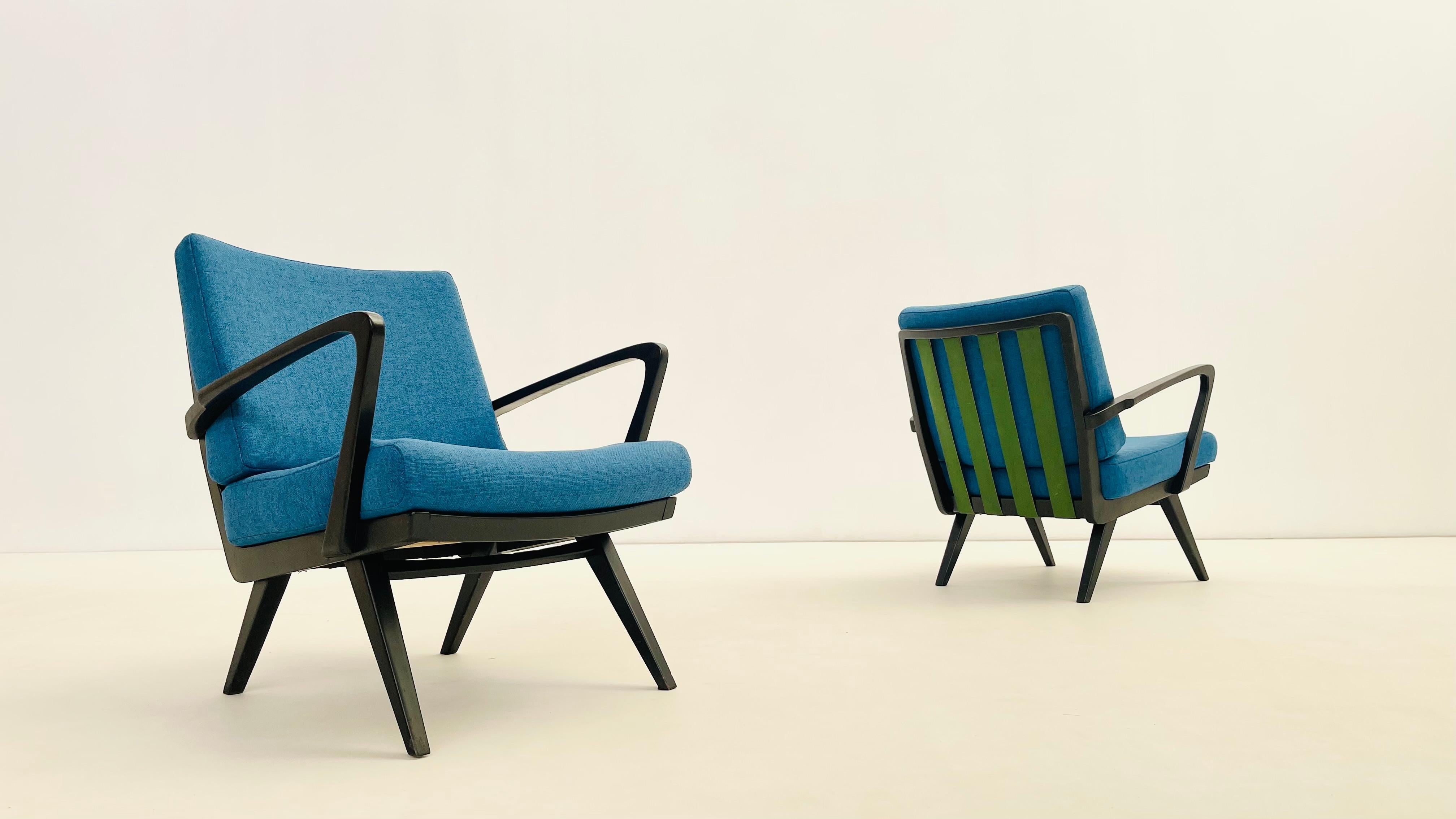 Cette élégante chaise longue est dotée d'un cadre noir robuste et de sangles en cuir vert qui maintiennent les coussins bleus incurvés fabriqués à partir d'un tissu durable et confortable. C'est le siège idéal pour lire, faire la sieste ou