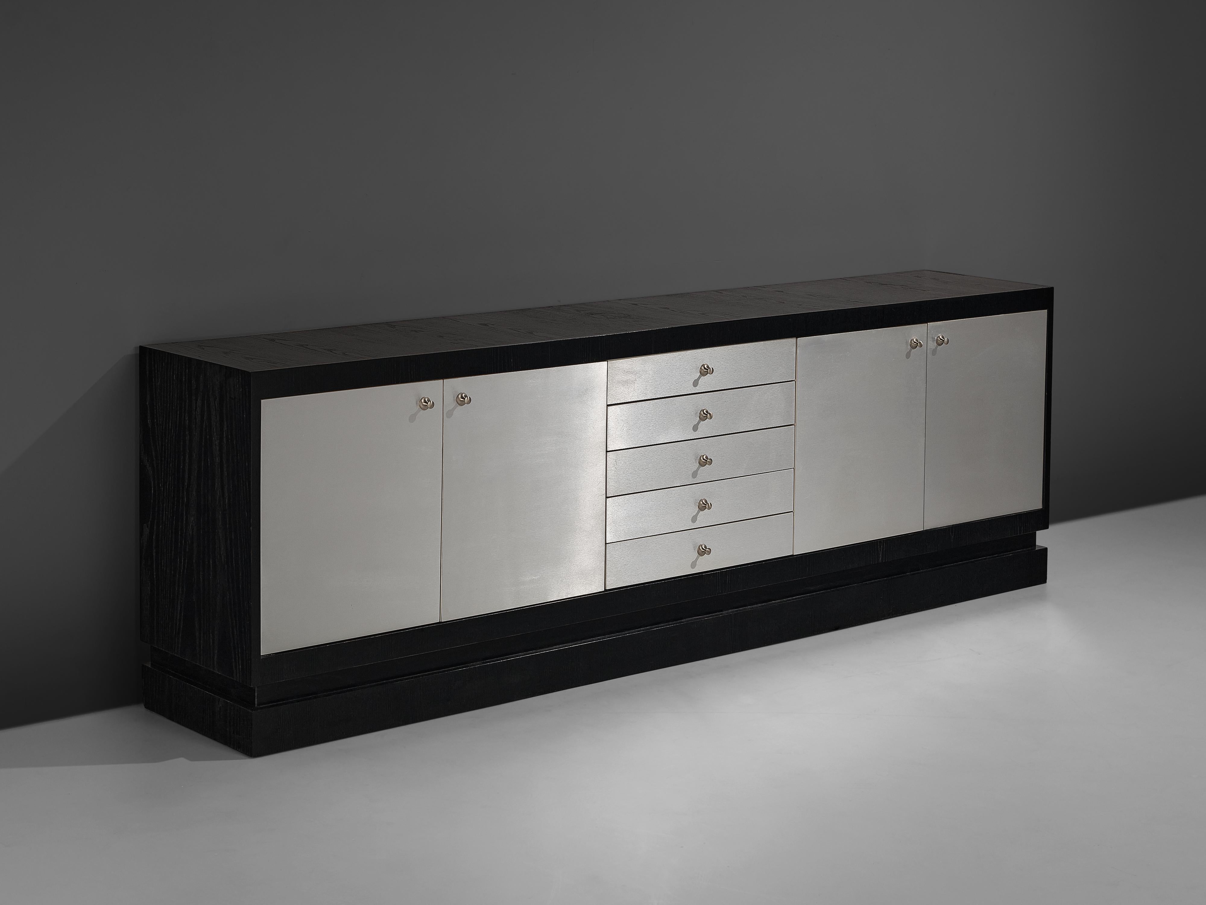 Sideboard, lacquered oak, aluminum, Belgium, 1970s 

Sideboard with aluminium plated doors and handles and a black wooden frame. The front is divided into two doors on both sides of a set of drawers in the middle. The frame and body of the sideboard