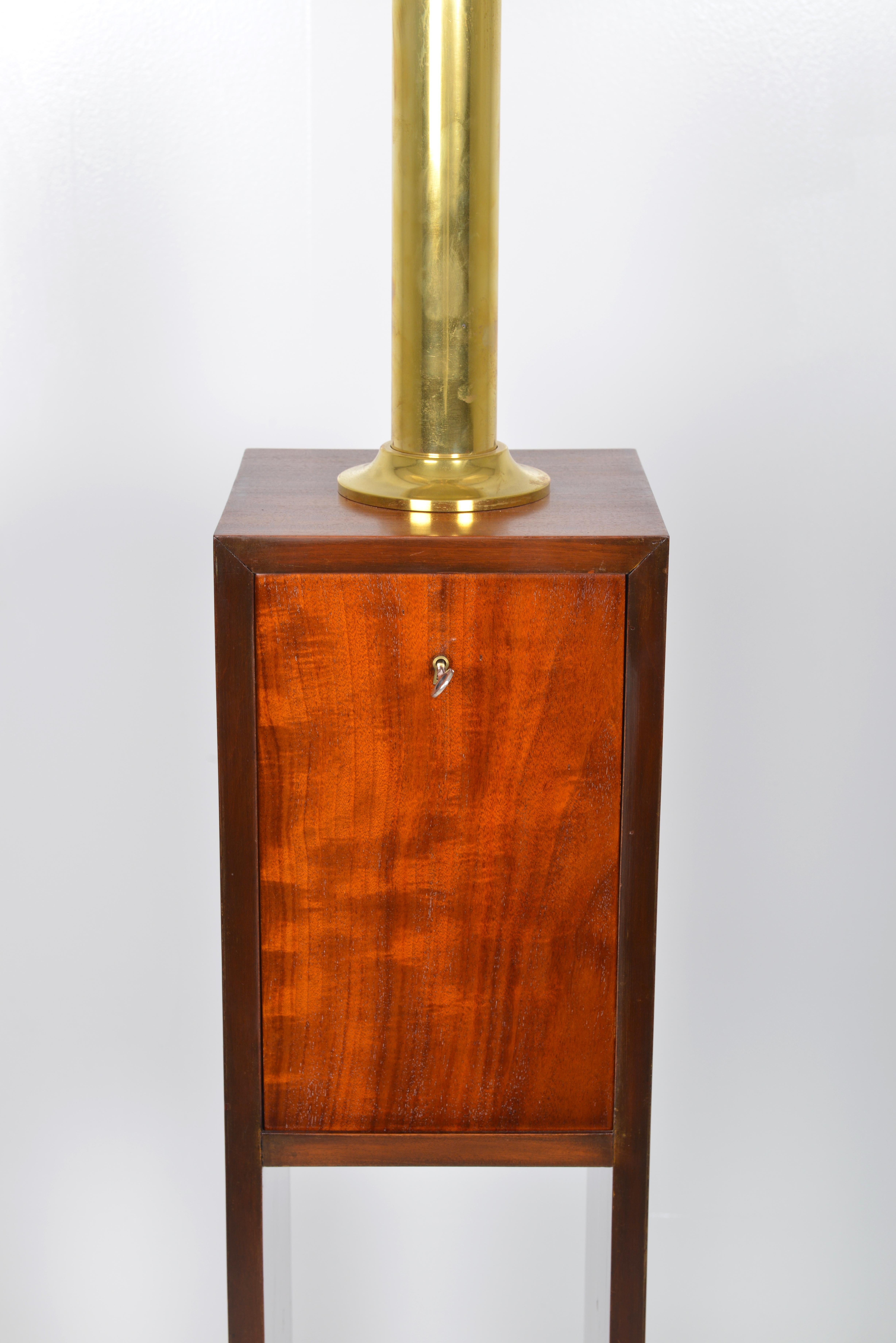 Extremely unusual library standard lamp made of solid mahogany, Belgian around 1930. The lamp features a wooden base with sweeping plinth, two bookshelves, a closed compartiment with drop front door, and on top of this a central brass uplighter and
