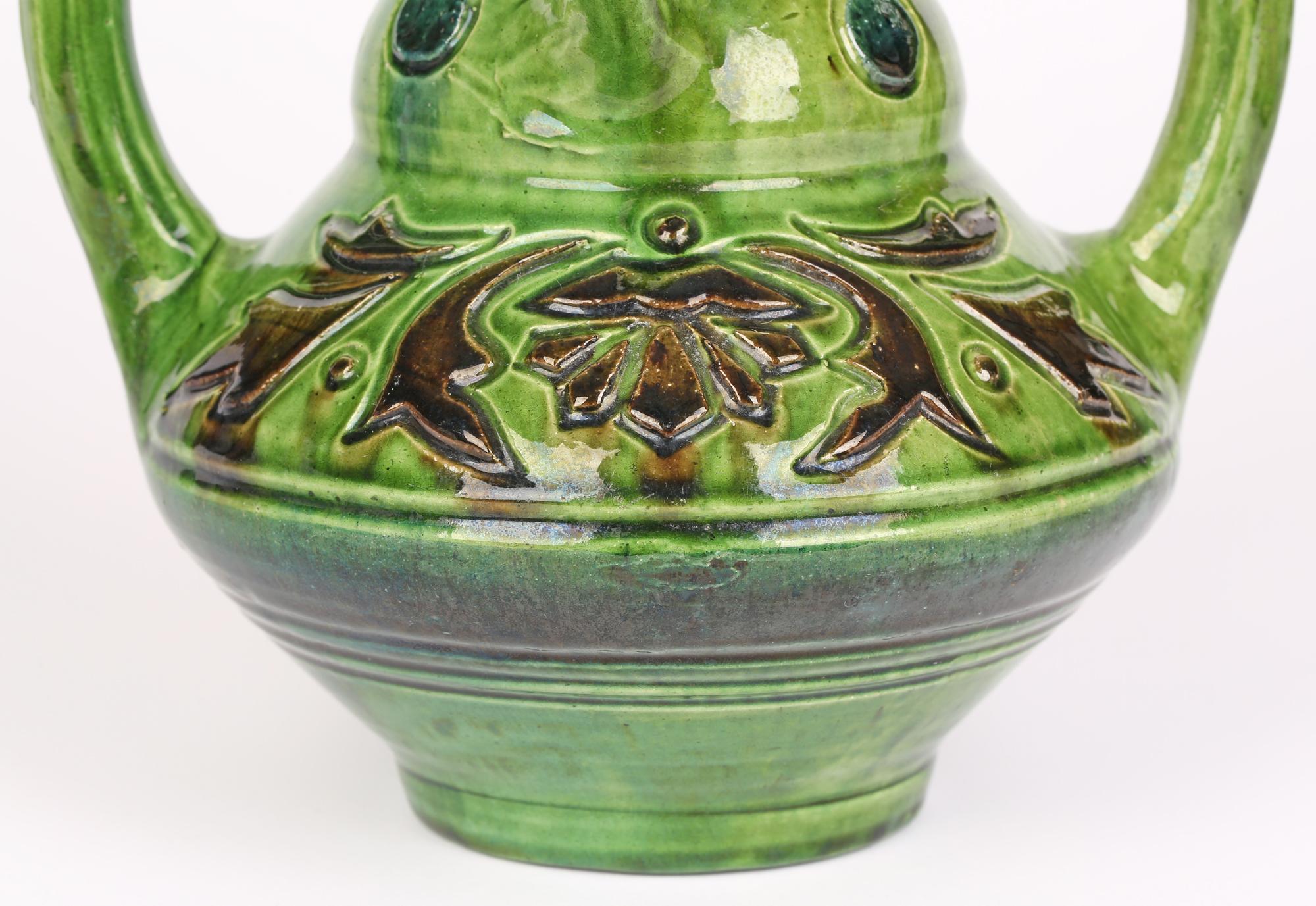 Un très élégant vase en poterie d'art belge Art Nouveau à quatre anses avec des motifs floraux stylisés datant d'environ 1900. Le vase repose sur un pied étroit et rond, avec un corps inférieur large et rond, un haut col profilé, deux grandes