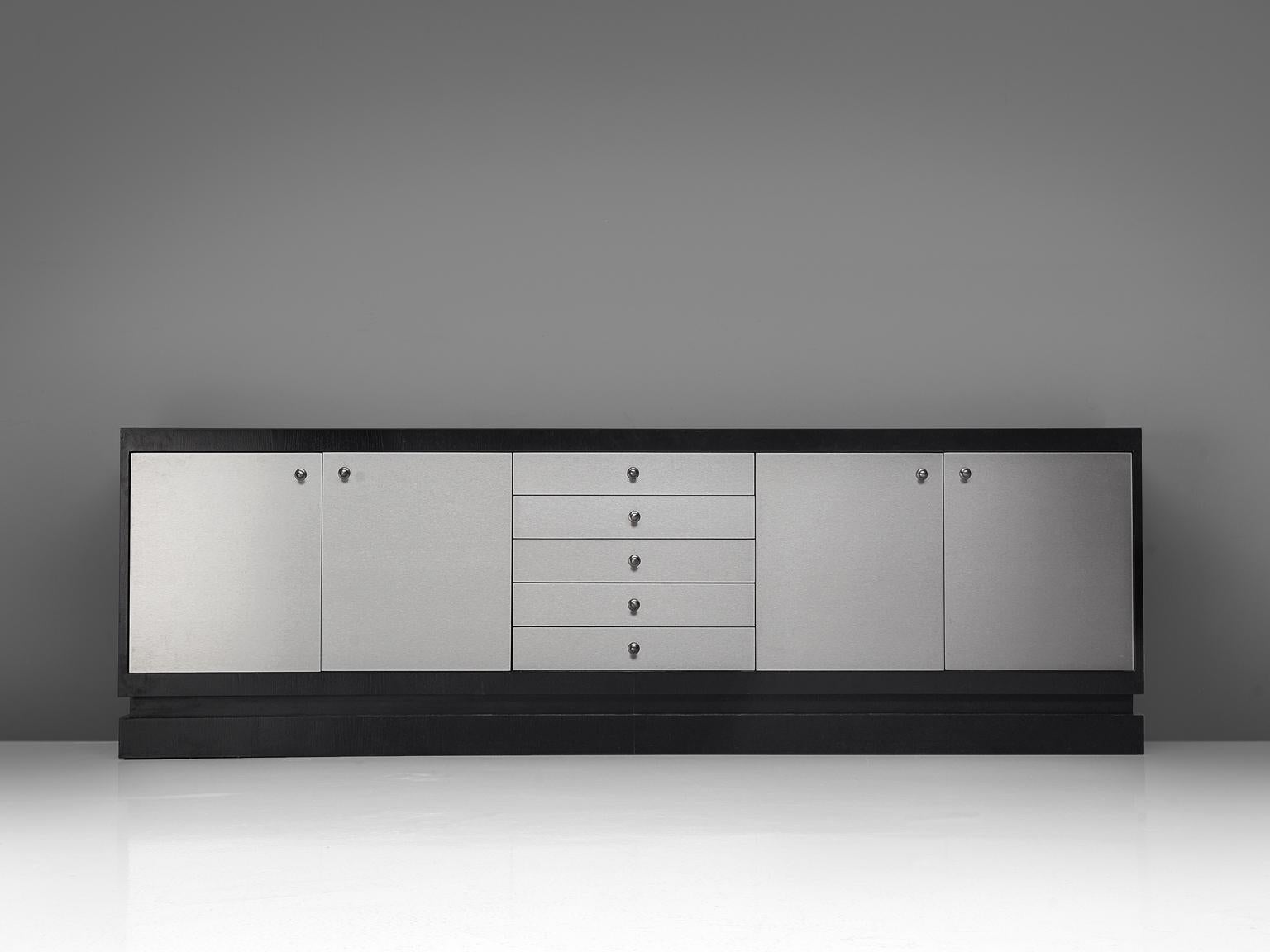 Sideboard, aluminum, wood, Belgium, 1970s.

Very minimal designed Belgian credenza with wonderful aluminum laminated door panels which create a real rich expression. Especially the combination with the black laminated outside which creates a high