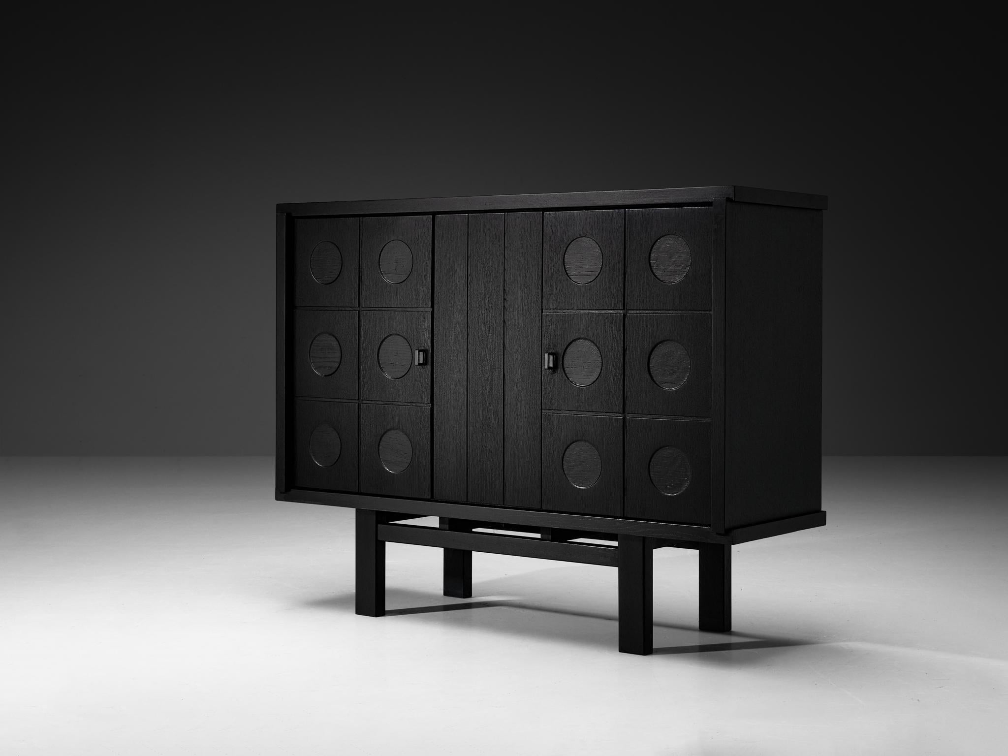 Armoire, chêne laqué, Belgique, 1970

Ce cabinet se caractérise par un rythme et un flux clairs, établis au moyen d'une mise en page bien pensée et tout à fait équilibrée. Les cercles sculptés attirent immédiatement l'attention et sont la signature