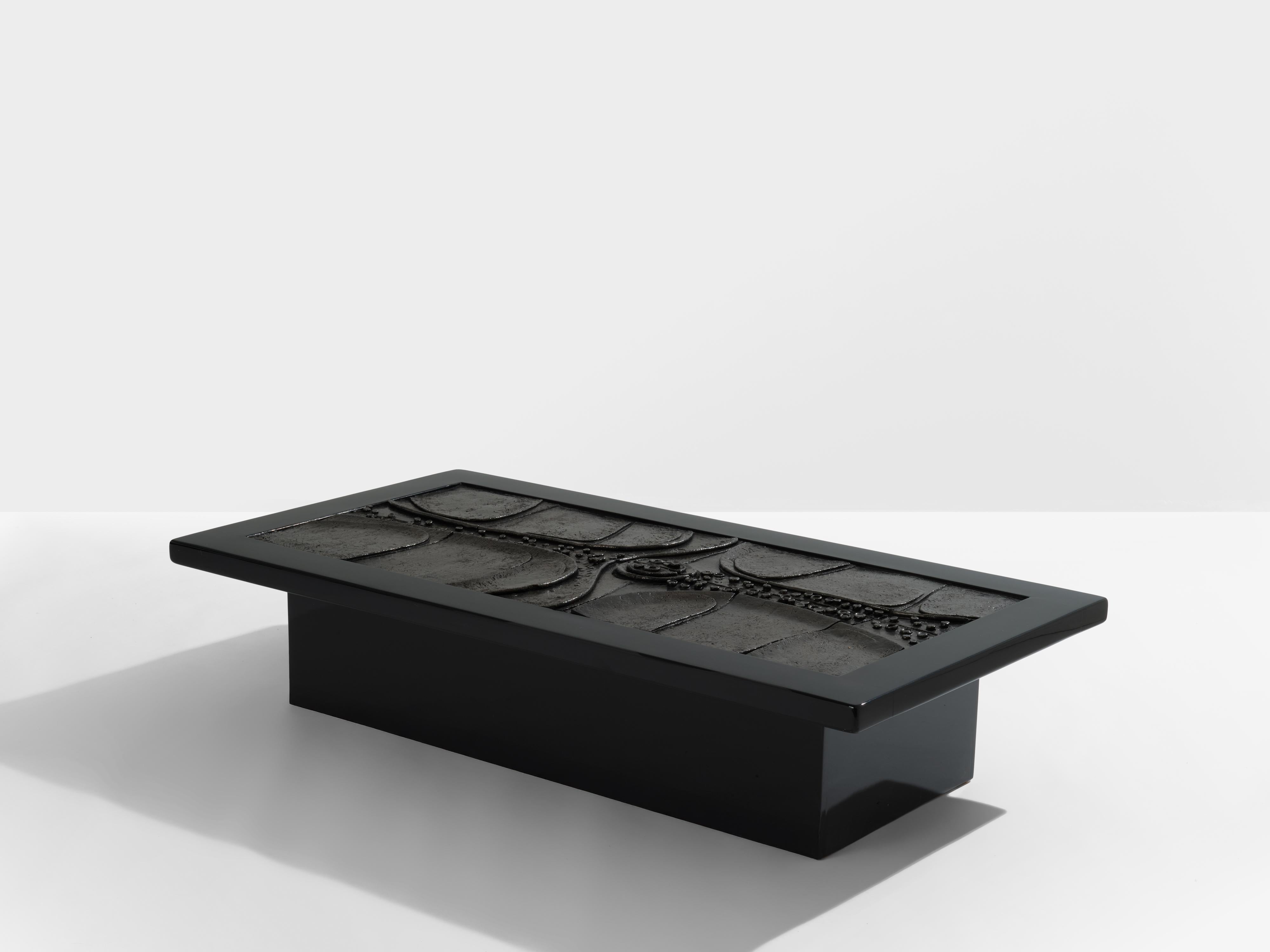 Mesa de centro brutalista única, obra del arquitecto y diseñador belga Erik Deforce en 1977. La estructura y los pies macizos lacados en negro enmarcan una escultura de cerámica patinada al carbón, que parece un cuadro abstracto posmoderno. La tabla