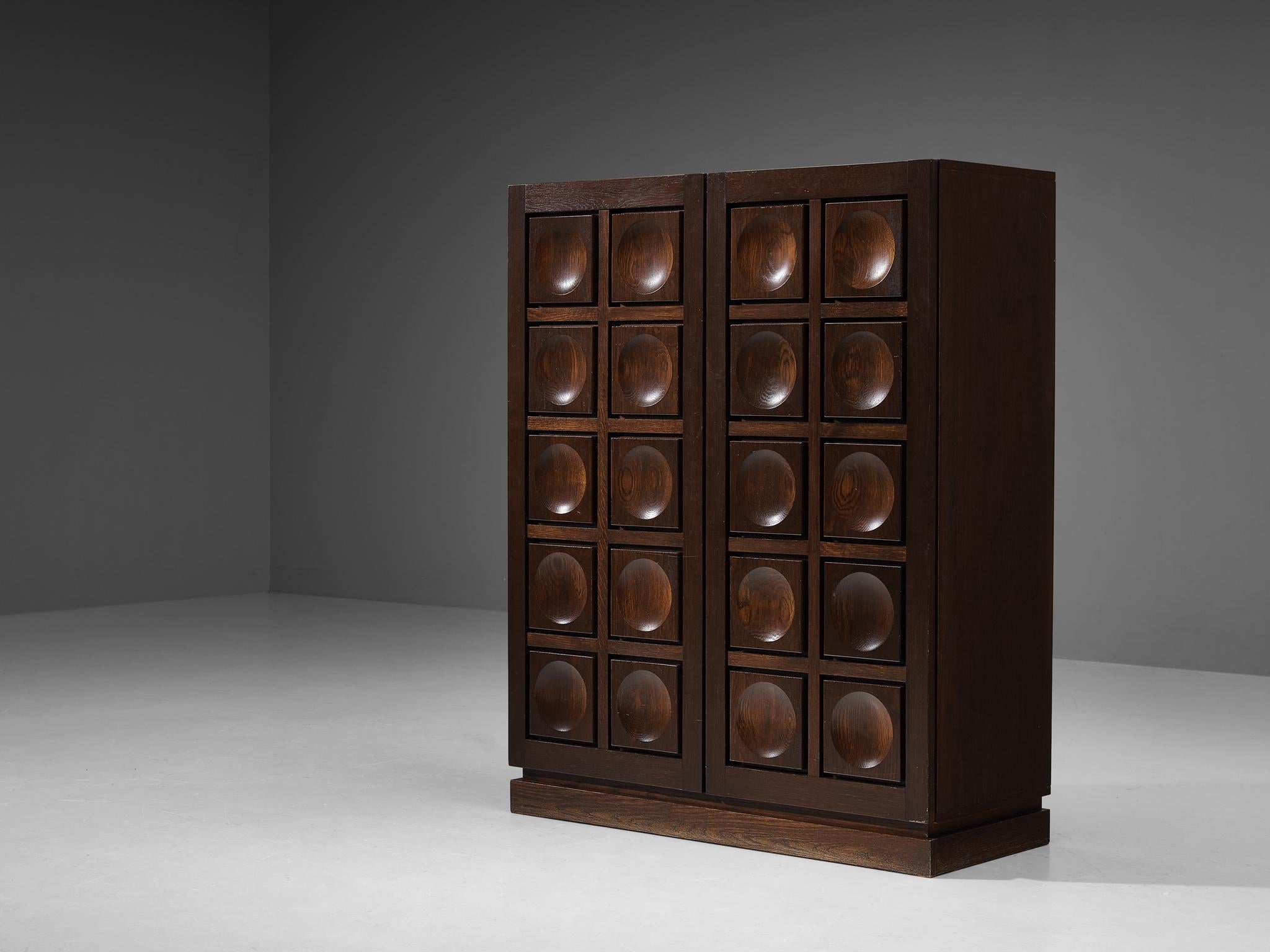 Highboard or cupboard, oak, Belgium, 1970s.

This very evocative cabinet features a clear rhythm and flow established by means of a well thought through lay out that is utterly well-balanced. The carved circles immediately catch the eye and are