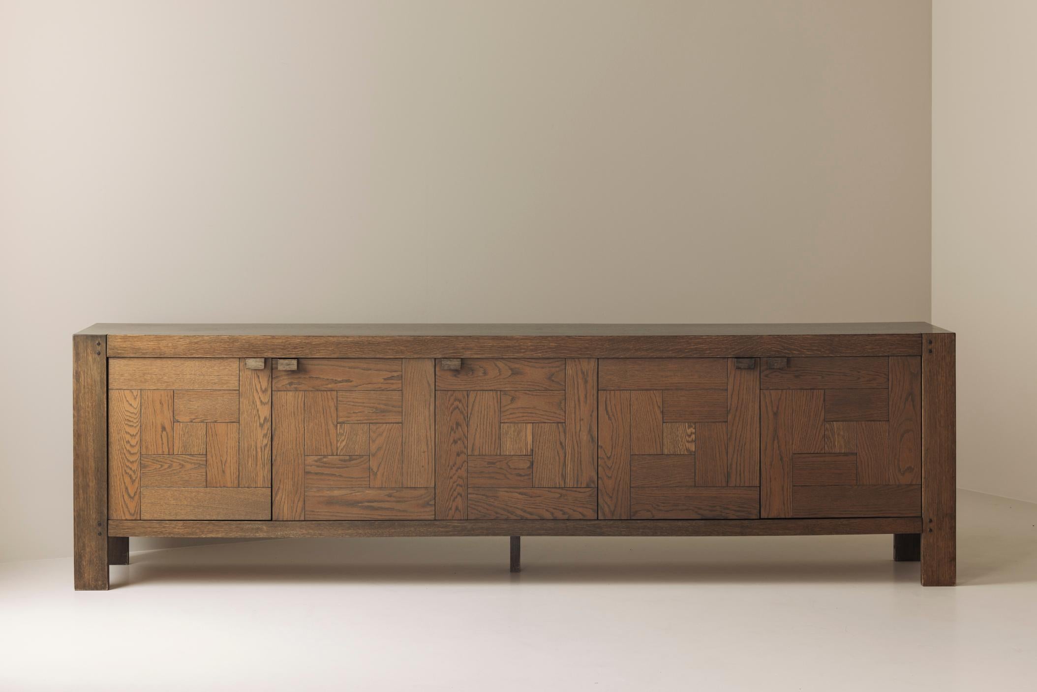 An outstanding work of Belgian Brutalist design, the “Modena” sideboard by Frans Defour was created in the 1970s and produced by Defour, Belgium. Crafted from solid stained oak, the piece stands out with its striking graphical parquetry front, where