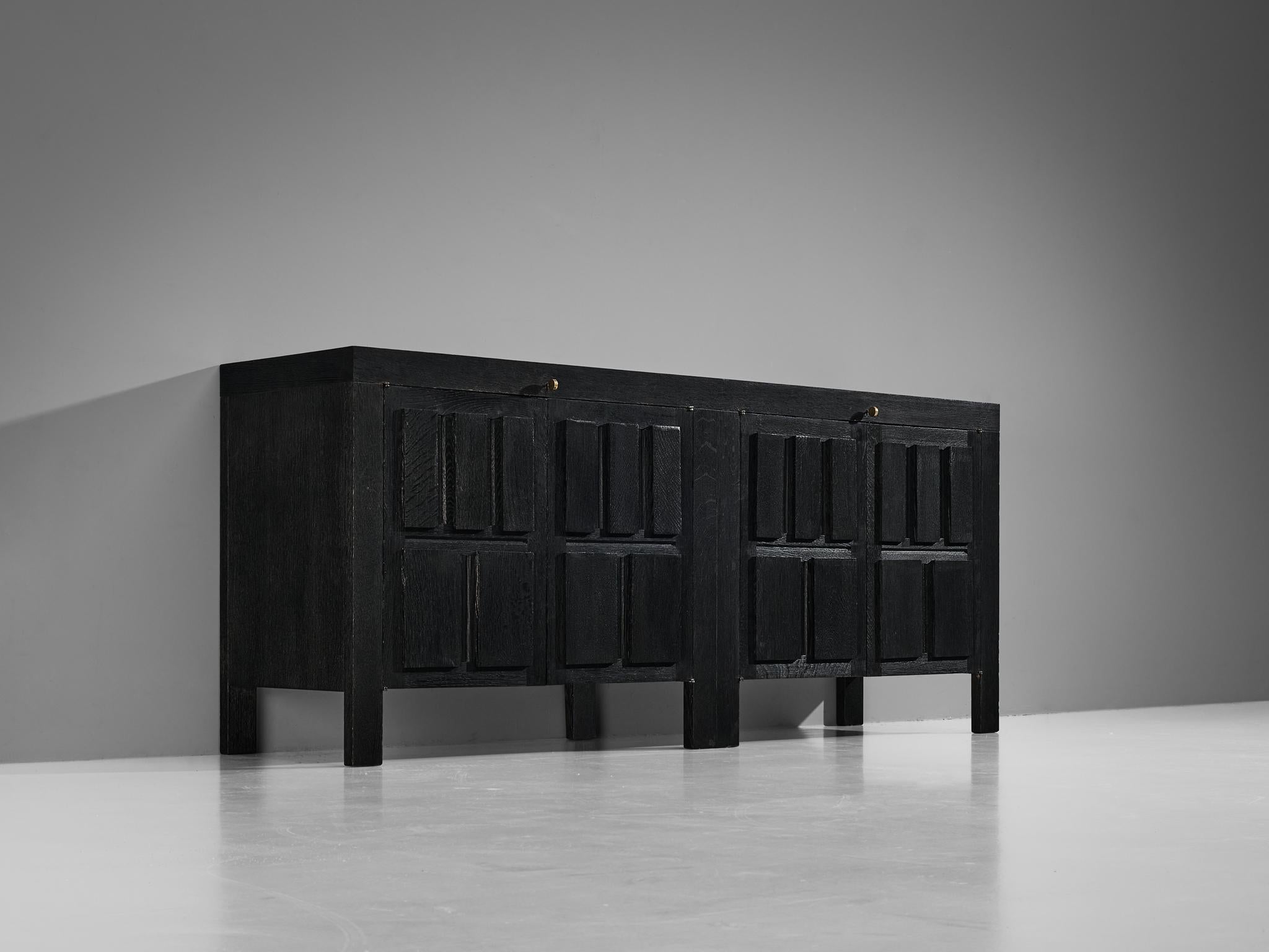 Sideboard, black lacquered oak, metal, Belgium, 1970s

This Belgian sideboard by features a clear rhythm and flow established by means of a well thought through lay out that is utterly well-balanced. The carved geometrical shapes on the door panels