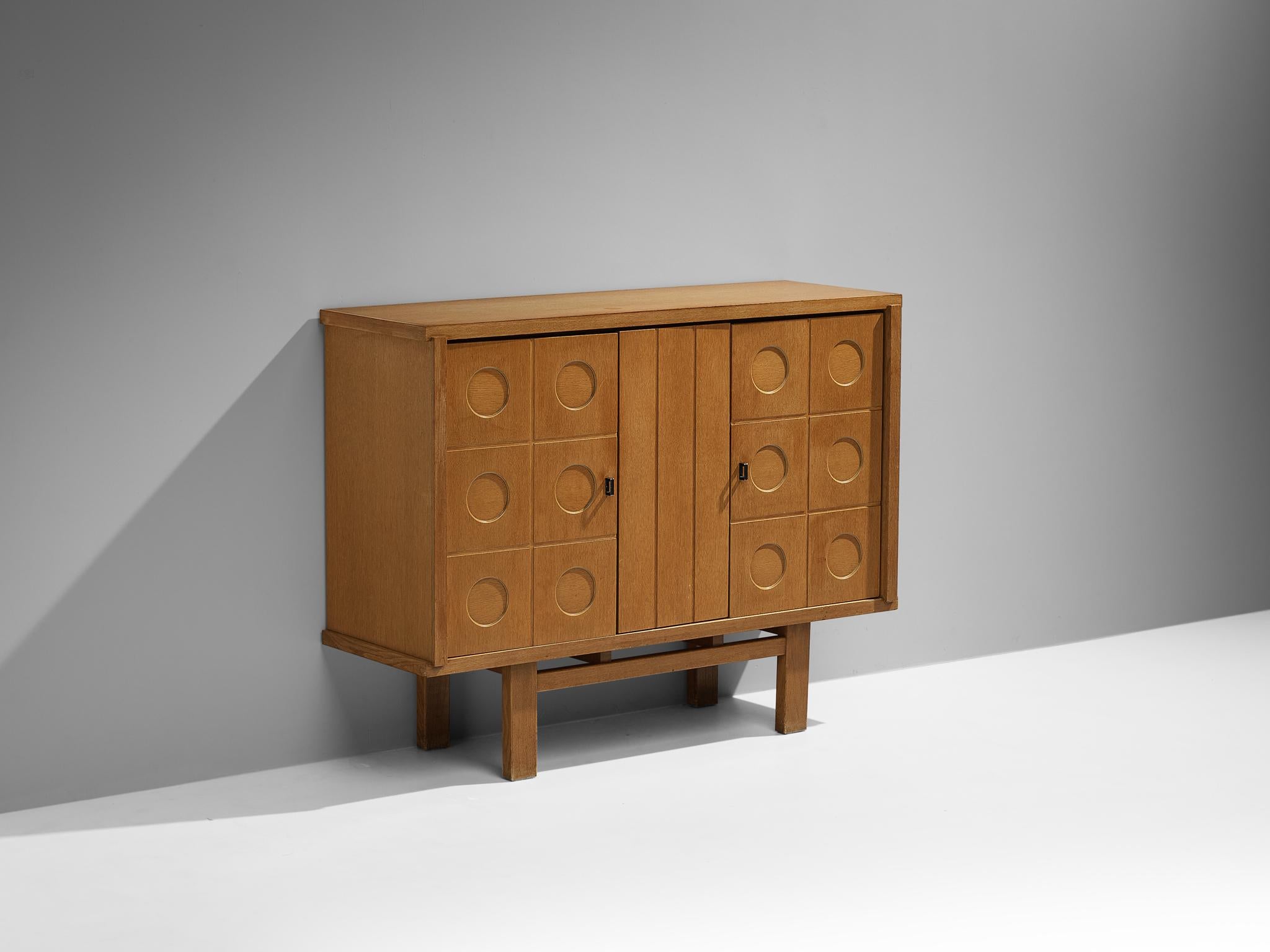 Cabinet or sideboard, oak, coated steel, Belgium, 1970s.

This cabinet features a clear rhythm and flow established by means of a well-thought-out lay out that is utterly well-balanced. The carved circles immediately catch the eye and are the