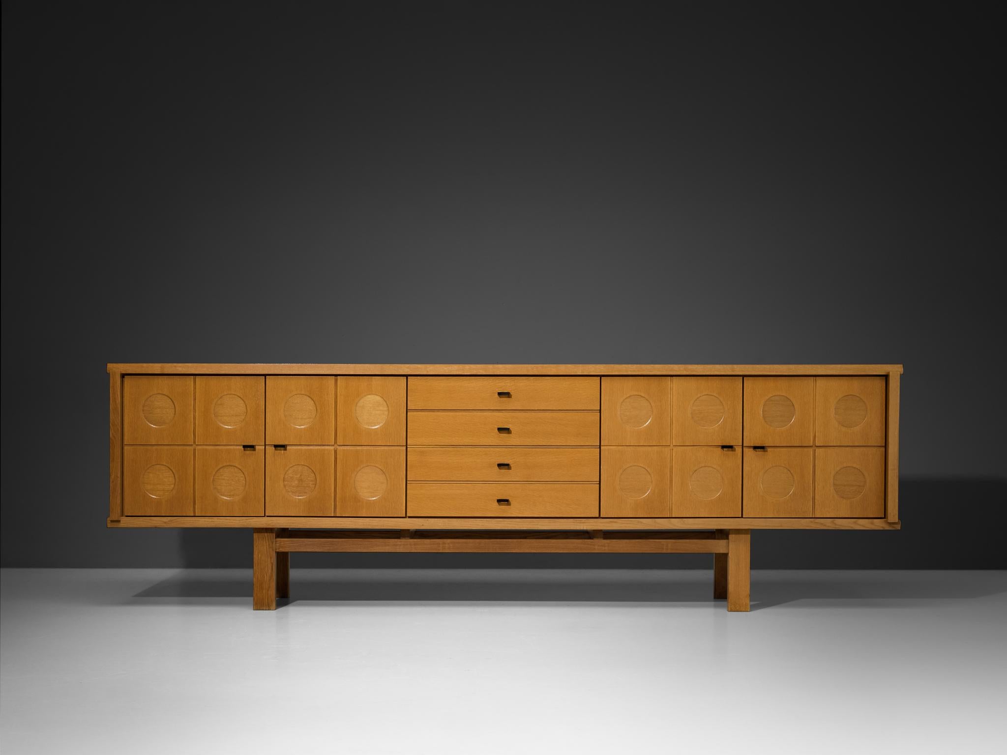 Sideboard, oak, lacquered aluminum, Belgium, 1970s

This sideboard features a clear rhythm and flow established by means of a well-thought-out lay out that is utterly well-balanced. The carved circles immediately catch the eye and are the signature