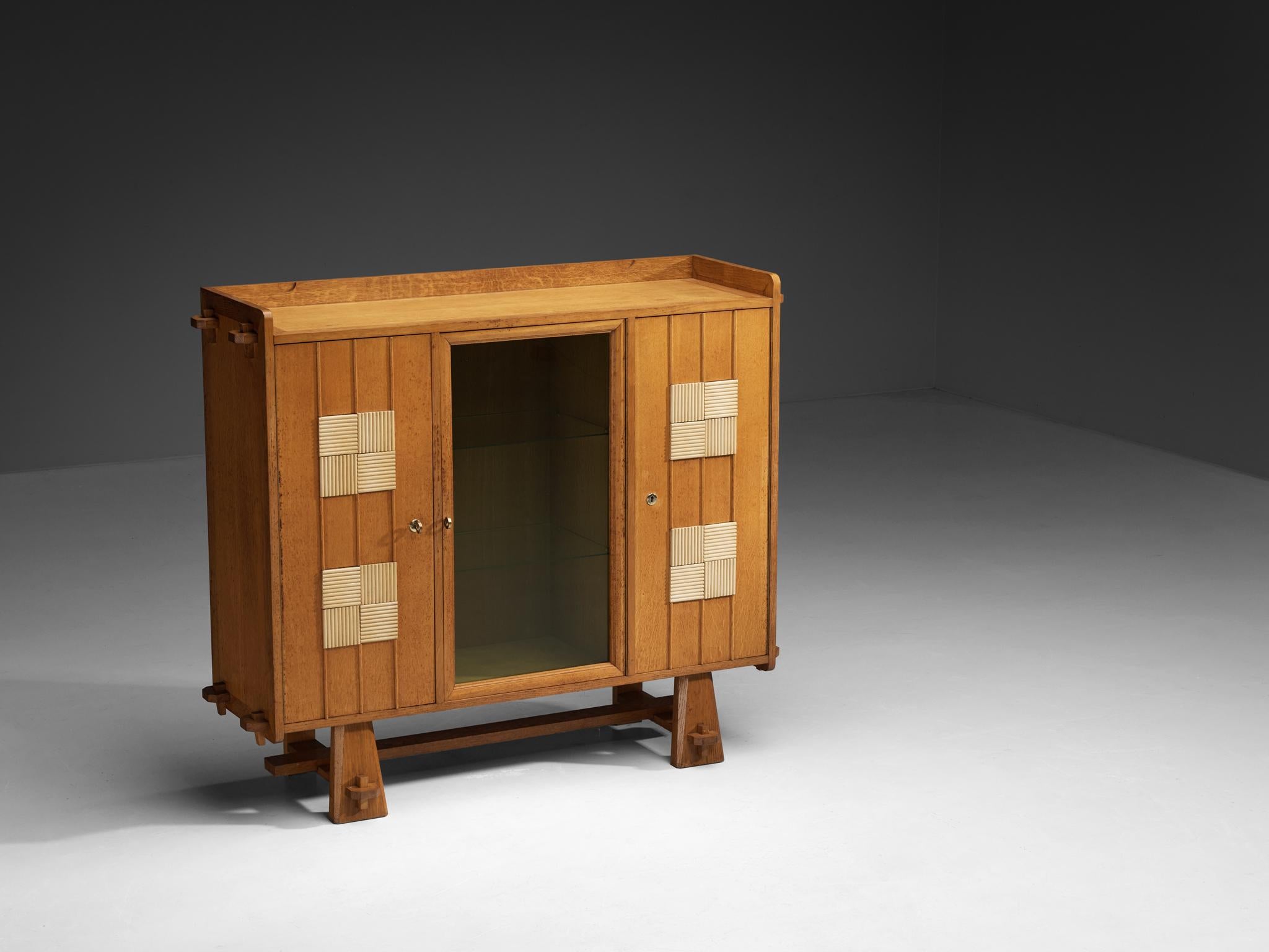 Armoire, chêne, verre, Belgique, années 1970. 

Cette armoire belge présente de beaux détails artisanaux dominés par une forme robuste réalisée principalement en chêne massif avec des panneaux en verre. Le meuble comporte une porte centrale en