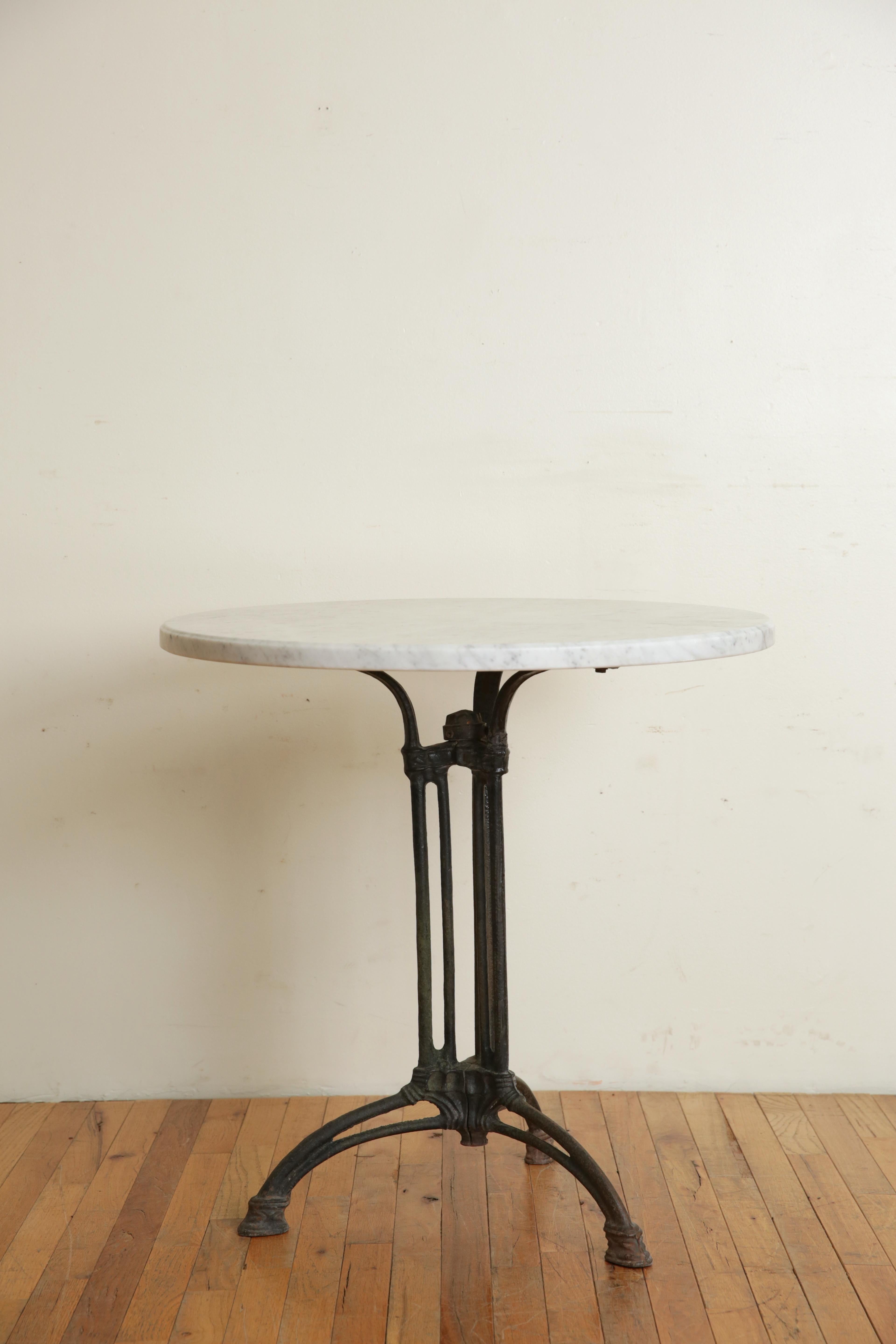 Having a (later) circular molded edge marble top atop a cast iron tripartite base with hoof-ish feet