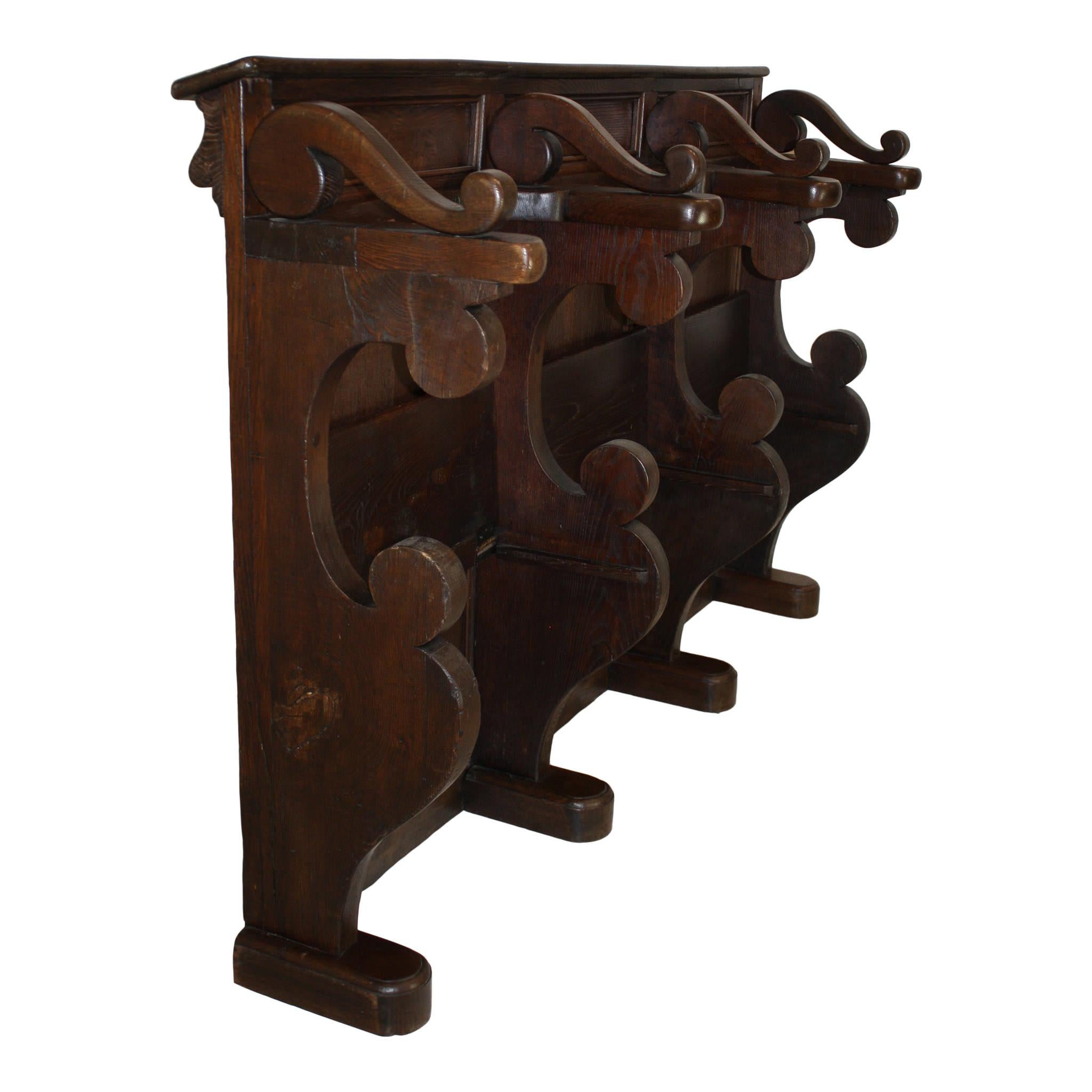 Some call it a church pew, others say it is a choir stall. Regardless of the term you use, this rare bench is remarkable. It is comprised of three sections, divided by C-scroll partitions, with a folding seat in each. The seats rise for standing or