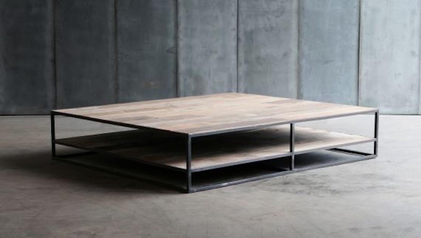 Elegante fusión de fuerza industrial y calidez orgánica, esta mesa de centro belga hecha a mano presenta un tablero de suelo de teca antigua meticulosamente incrustado en un sólido armazón de acero ennegrecido. Diseñada pensando tanto en la función