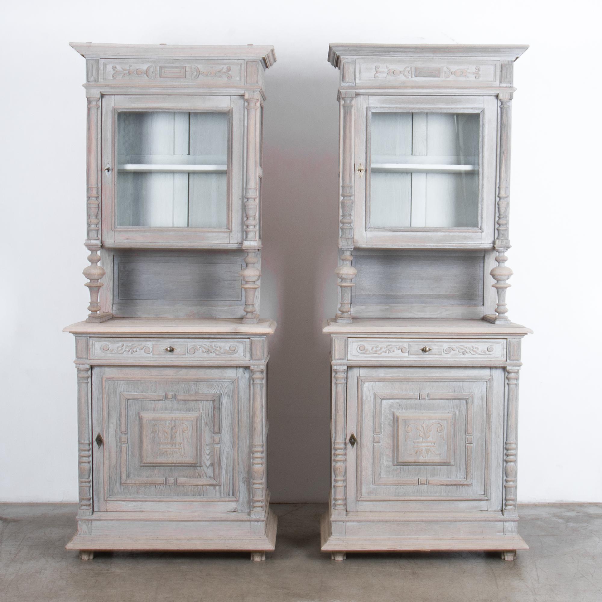 With a distinct French Provincial style, a pair of door and drawer buffet cabinets with integrated glass display storage. Featuring ornate carved frame and drawer panels, the bleached finish completely this piece, with a textured neutral color,