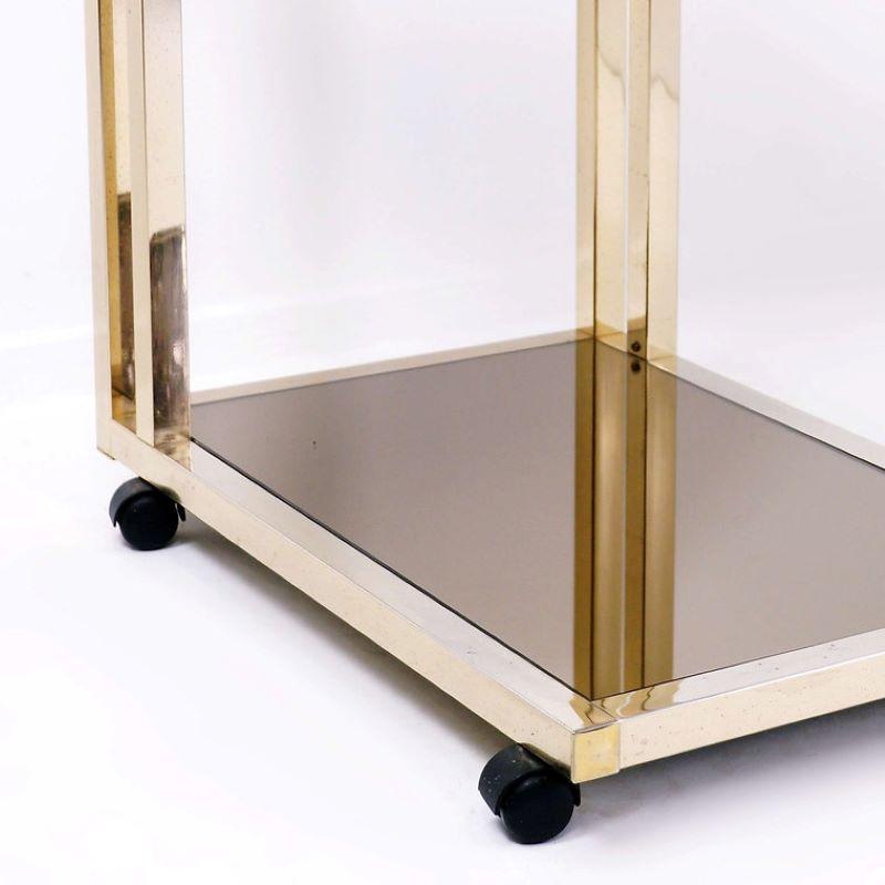 This modern, luxury bar cart was made in Belgium in the 1970s and produced by Belgo Chrome Dewulf Selection. It has a 23-karat gold plated frame. The trays are in smoked mirror glass
