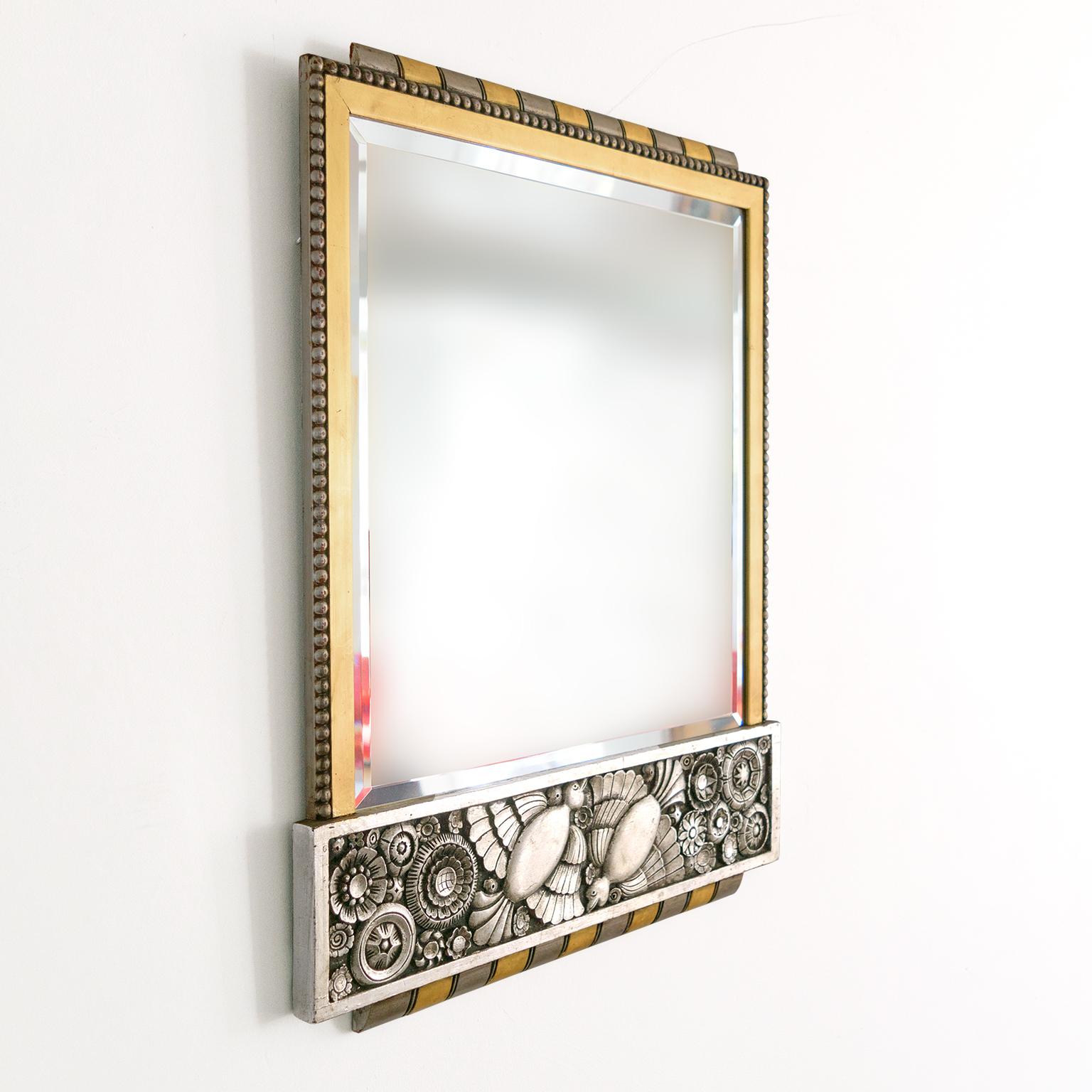 Belgian gilt and silver leaf wood, Art Deco mirror with a richly detailed frieze of stylized flowers and two birds in flight. The mirror has gold and silver striped moldings with tapered edges along the frame’s top and bottom. The two gilt side