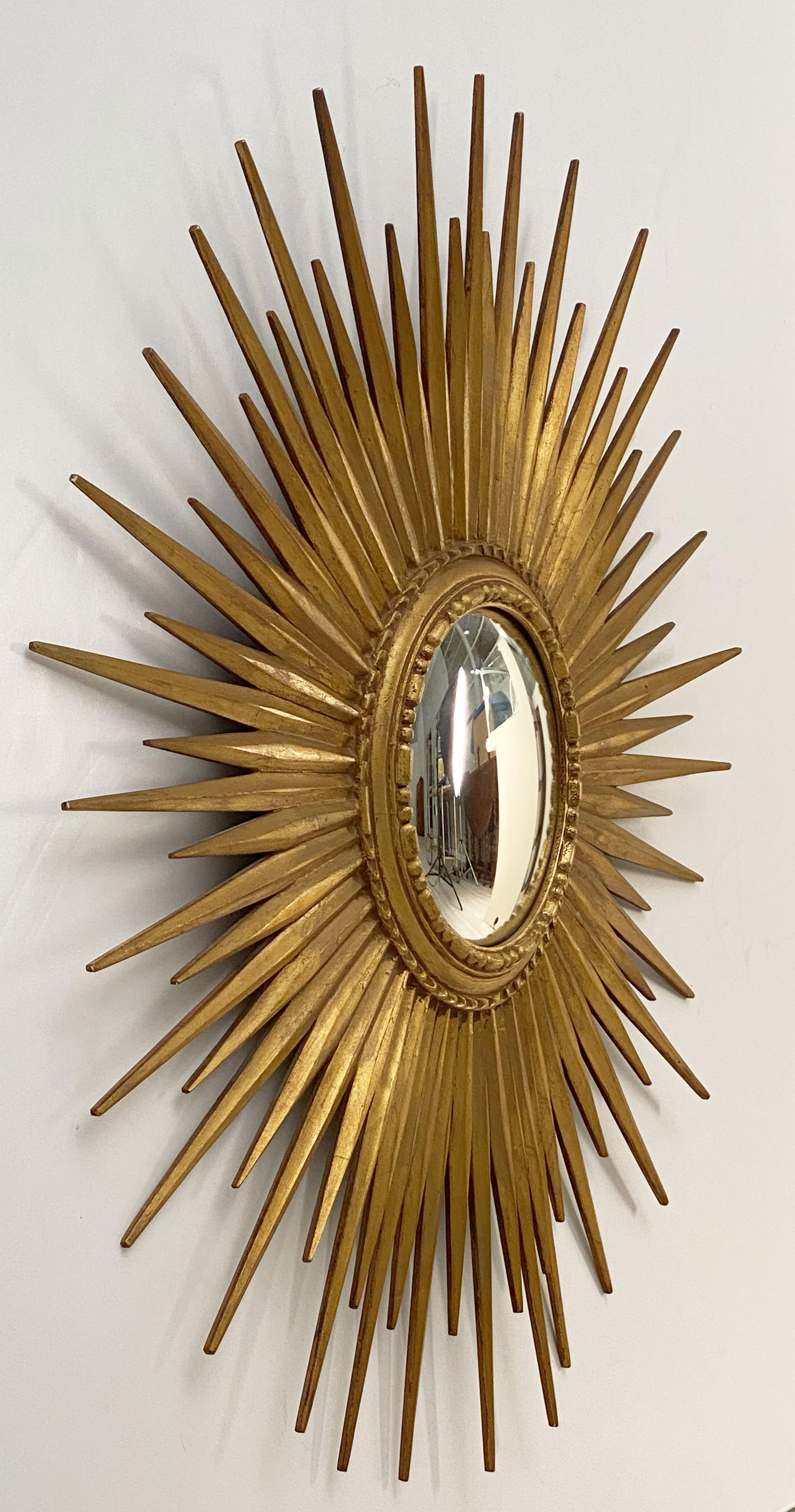 A lovely Belgian gilt sunburst (or starburst) mirror, 32 inches diameter, with a round, convex mirrored glass center in moulded frame. 
Far reaching undulating dramatic rays arranged around the original convex mirror plate, circa 1950.