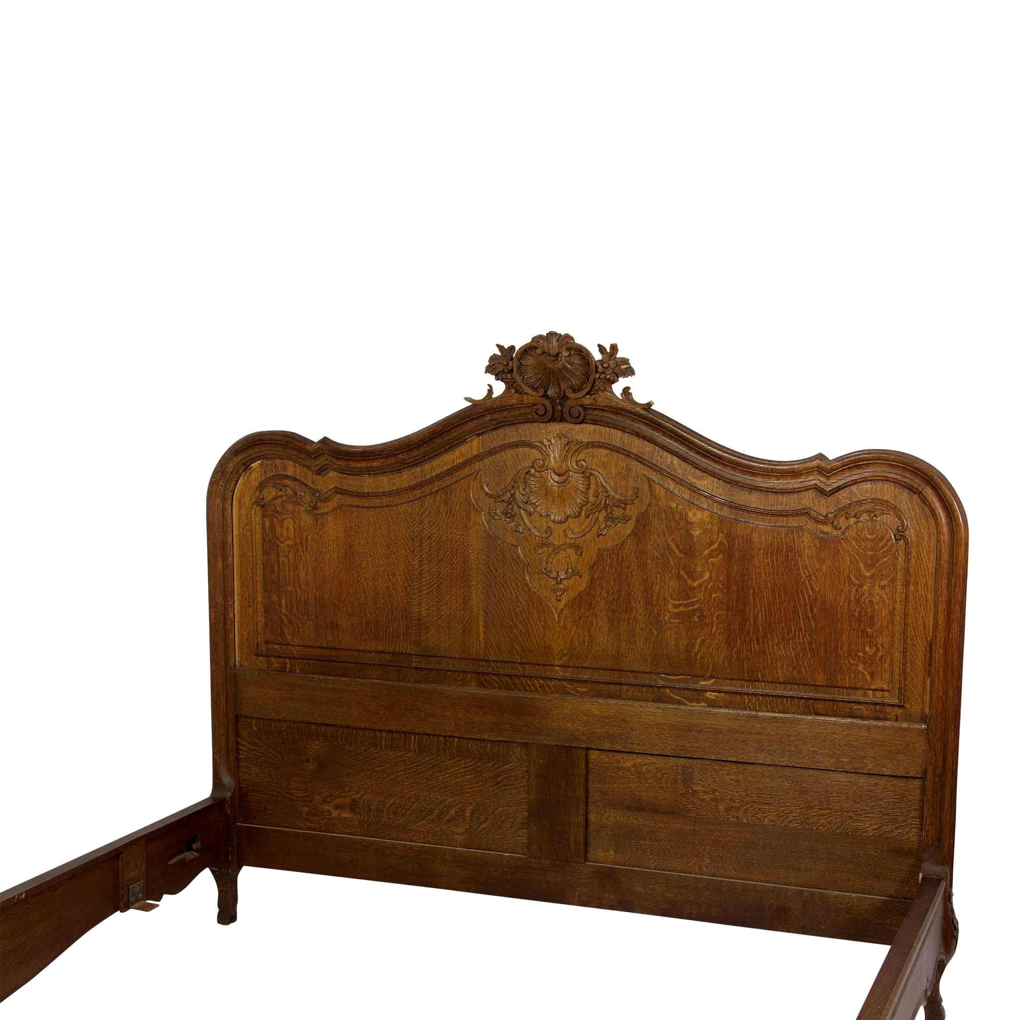 Crafted in Liege, Belgium, this Louis XV bed frame incorporates the beauty and quality of solid oak and quarter sawn oak. Identical carvings on the ached headboard and foot board feature a foliated shell and floral design. The frame is raised on