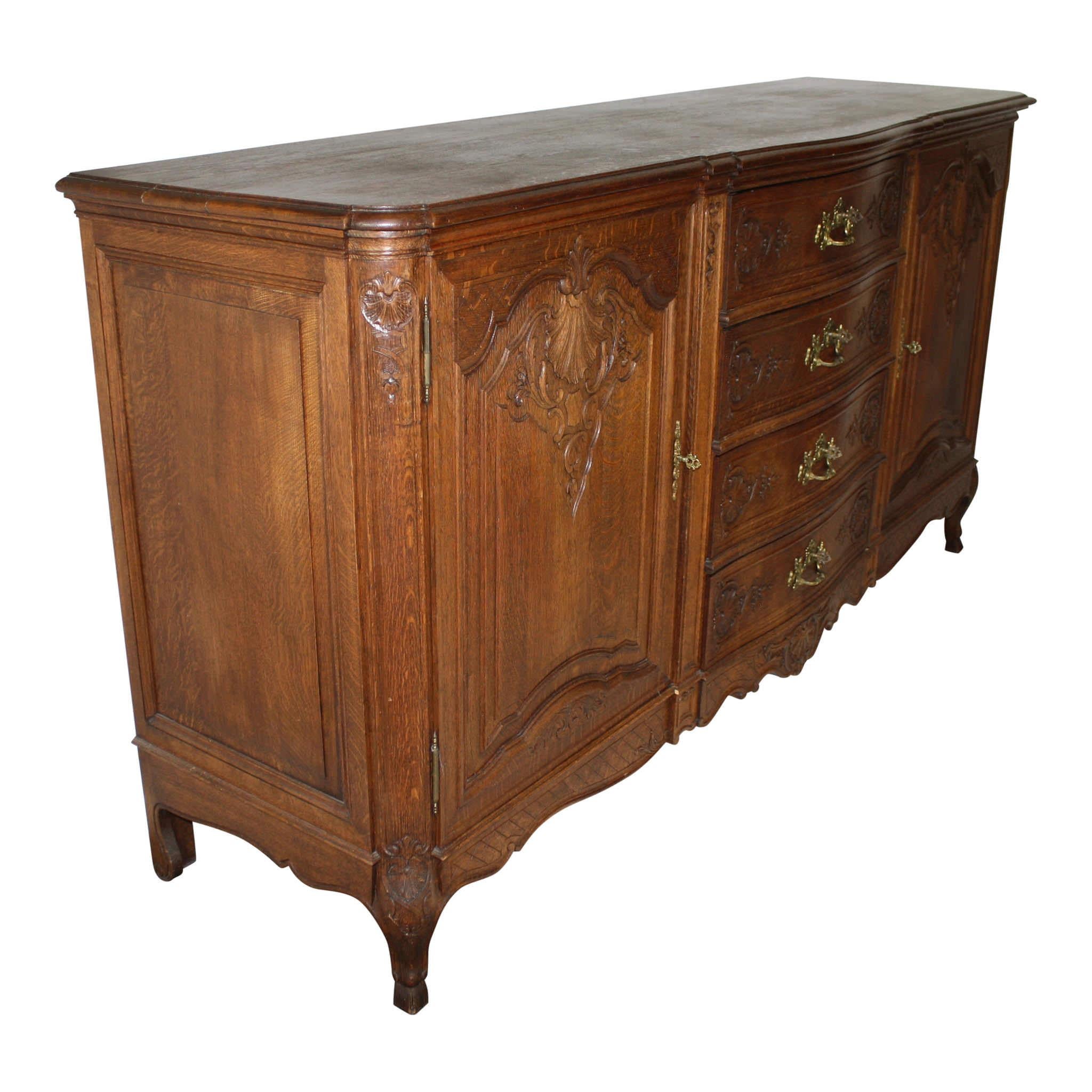 Crafted in Liege, Belgium, this turn of the century sideboard features four drawers flanked by side doors, which open to two adjustable shelves. Each of the drawers and doors has its own key. The drawers have ornamental escutcheons, which serve as