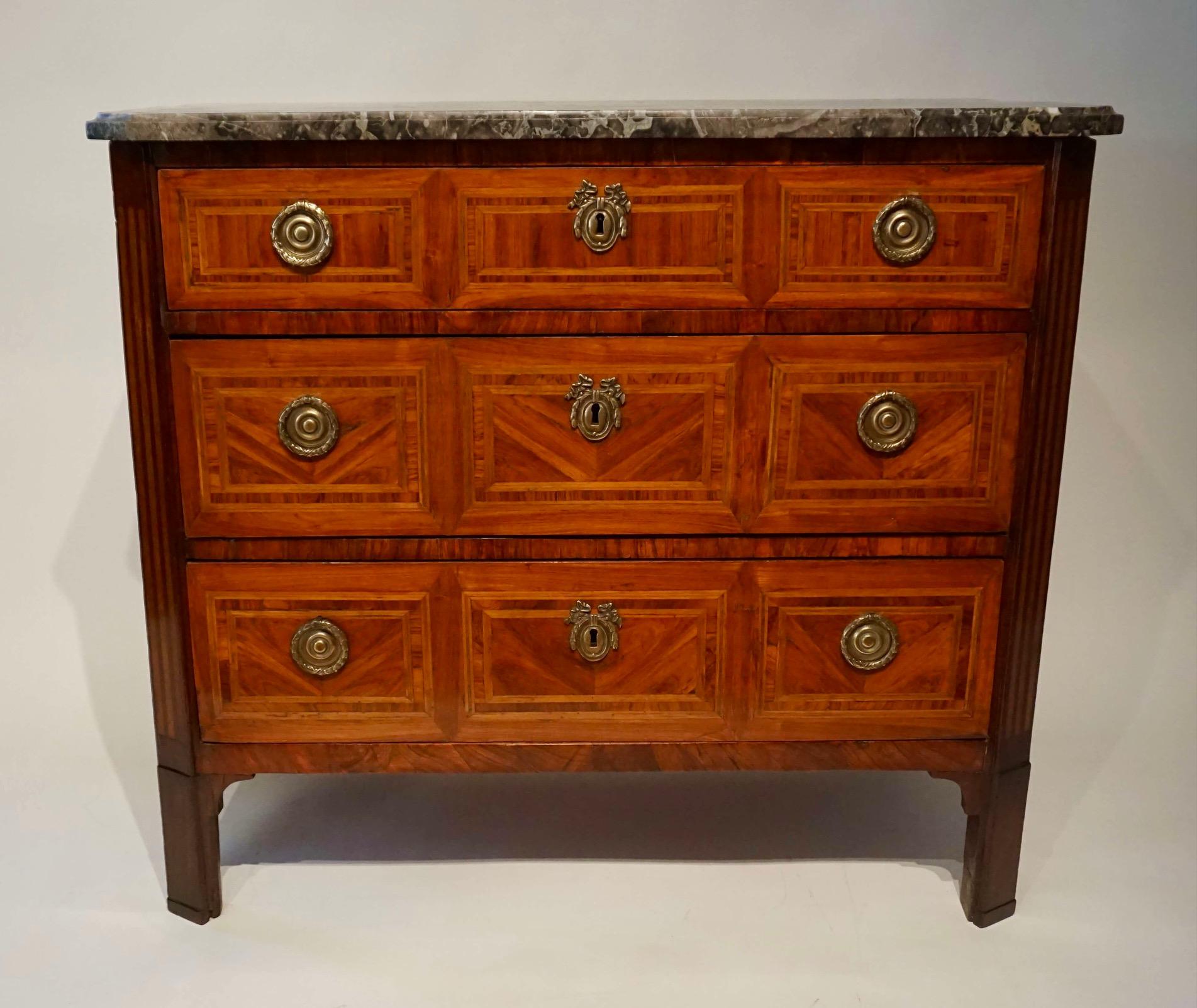 Belgian circa 1790 Louis XVI three-drawer commode having original Saint-Anne grey and white marble top above tulipwood, boxwood, and fruitwood parquetry veneered case with original silvered-brass pulls and escutcheons.