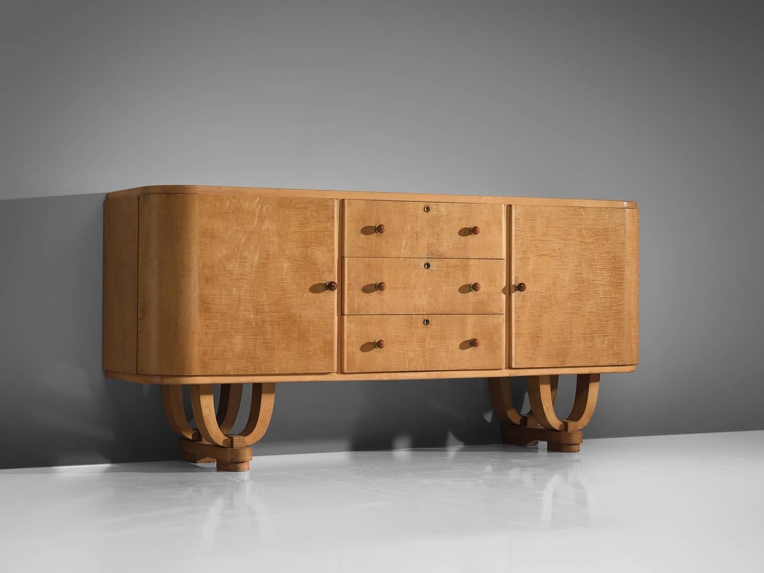 Sideboard, maple, polyester, Belgium, 1950s. 

This cabinet has a light maple wooden construction. The base of this credenza is made from sculpted, bent wood. The doors are detailed with brass key hole and orange to salmon colored bakalite handles.