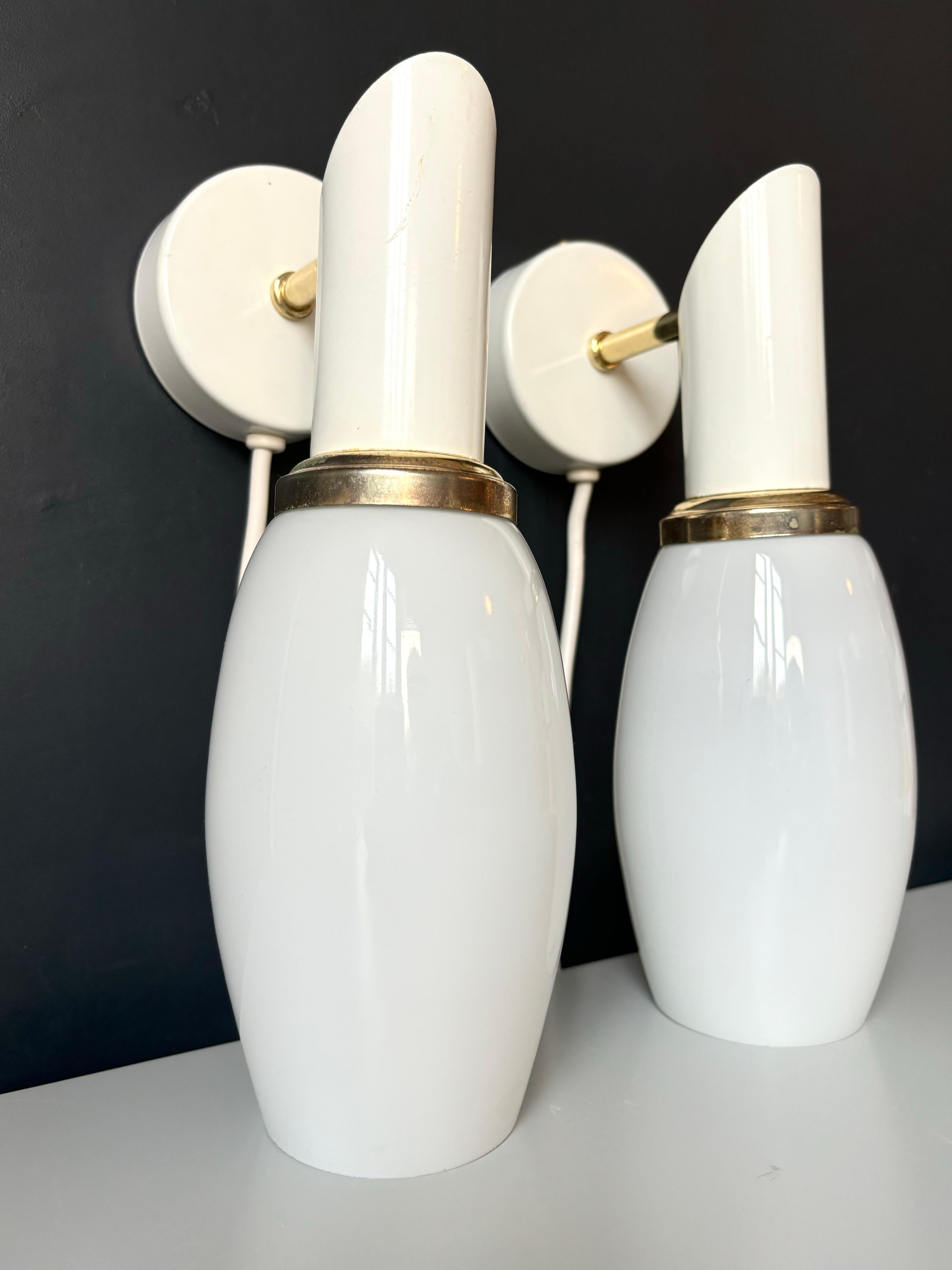 Pair of vintage glass, brass and metal wall lights by Massive Lighting. Sleek opaline glass shade on white and brass mount with slender brass arm. Label on the inside of both items. Beautiful vintage condition. 
Belgium, 1990s.
Price is for the pair.