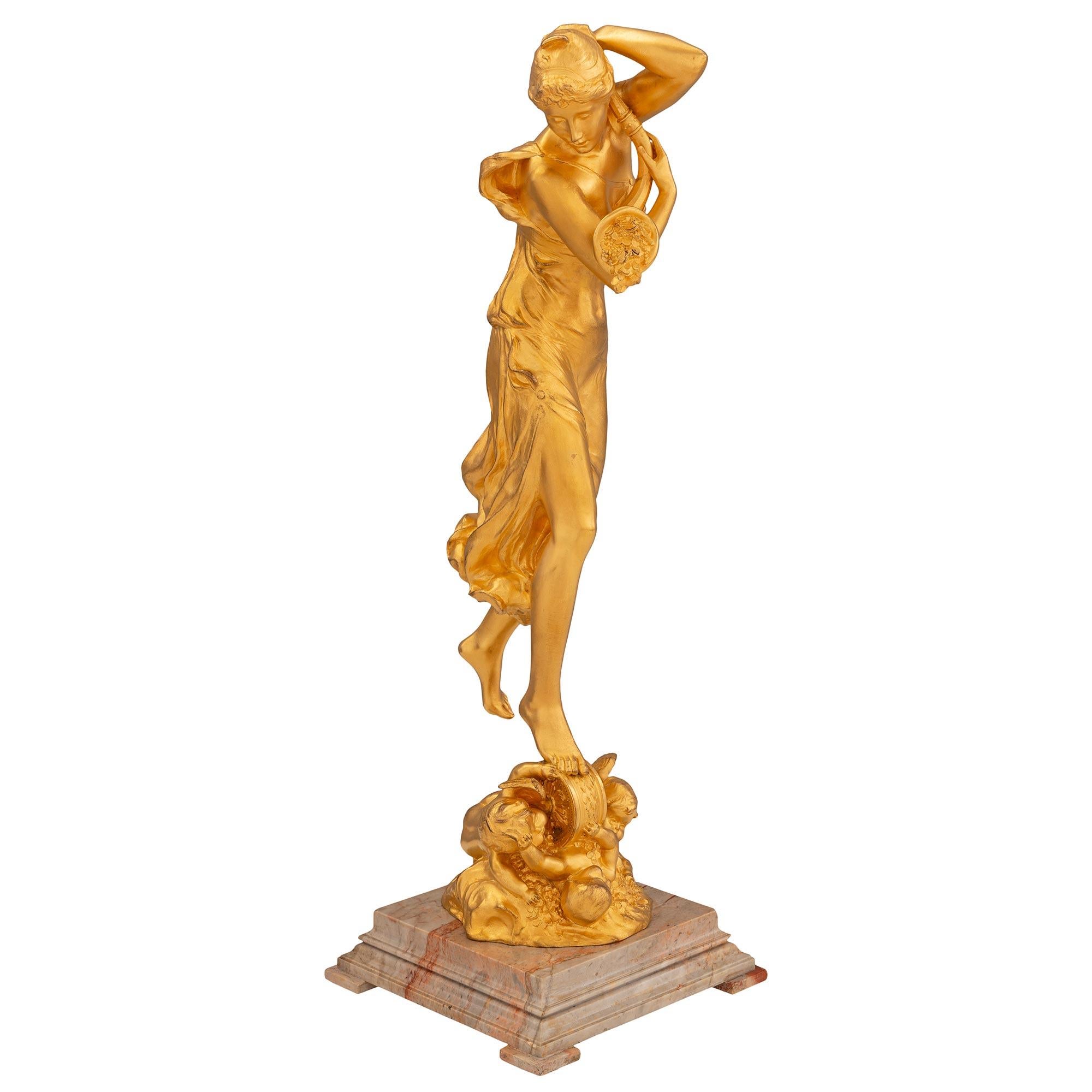 Une élégante statue en bronze doré et marbre Sarrancolin de style Louis XVI, signée Charles Samuel 1894 et Petermann Fondeur Bruxelles. La statue est surélevée par une belle base en marbre Sarrancolin tacheté à gradins, avec des pieds en bloc
