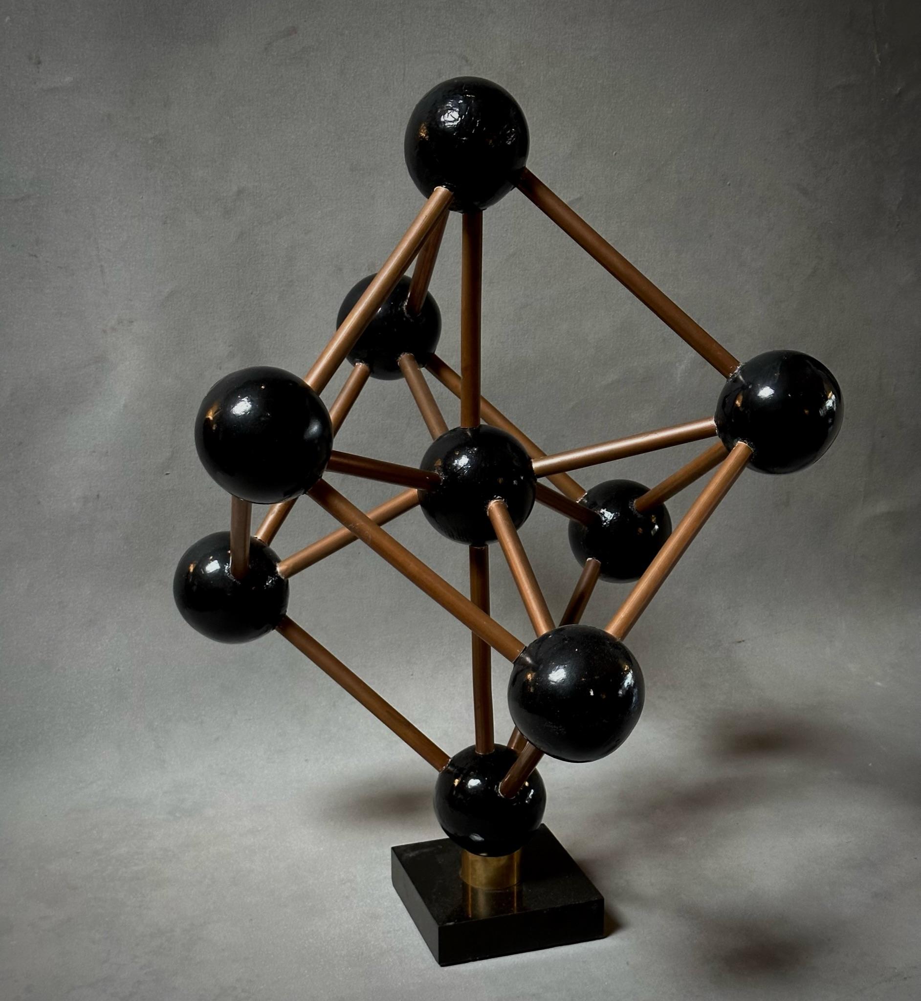 This mid-century geometric model from Belgium showcases ebonized wood spheres linked by copper-toned metal rods, arranged in an eye-catching modular pattern. Mounted on a sleek black marble base, this piece combines art and science, making it a
