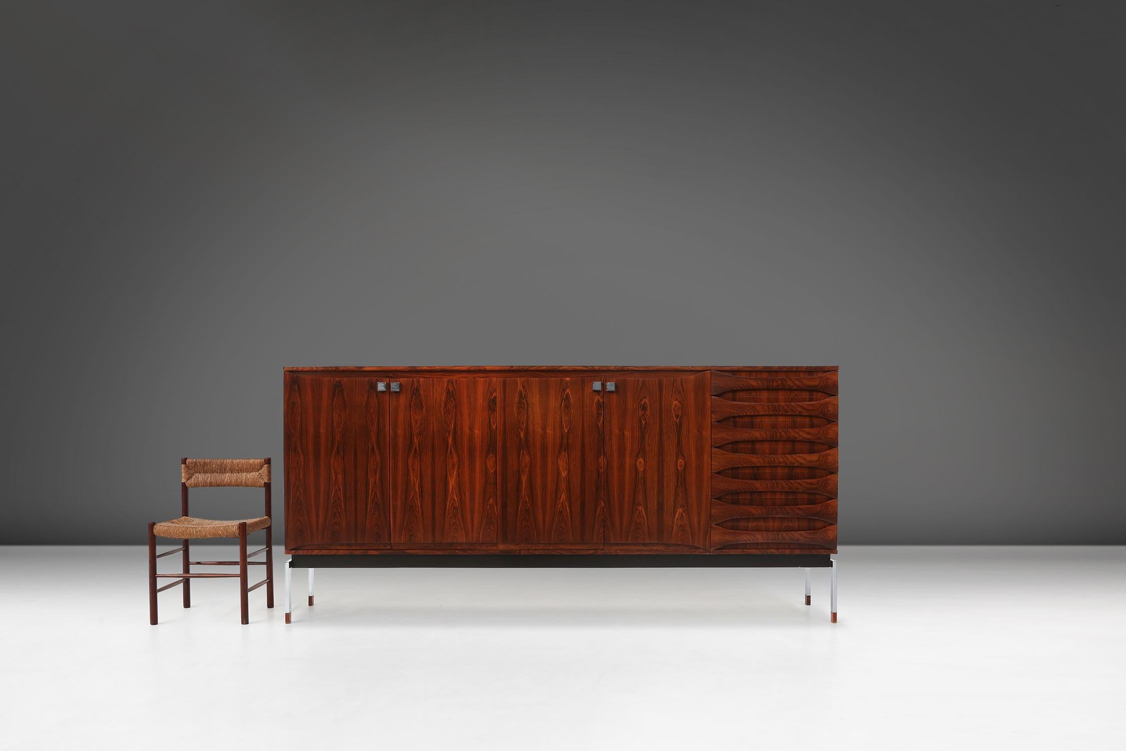 This mid-century highboard made in 1960s Belgium is a stylish and practical piece of furniture that fits perfectly into a modern interior. It is made of high-quality rosewood veneer, a type of wood known for its warm colour and fine grain.
It has a