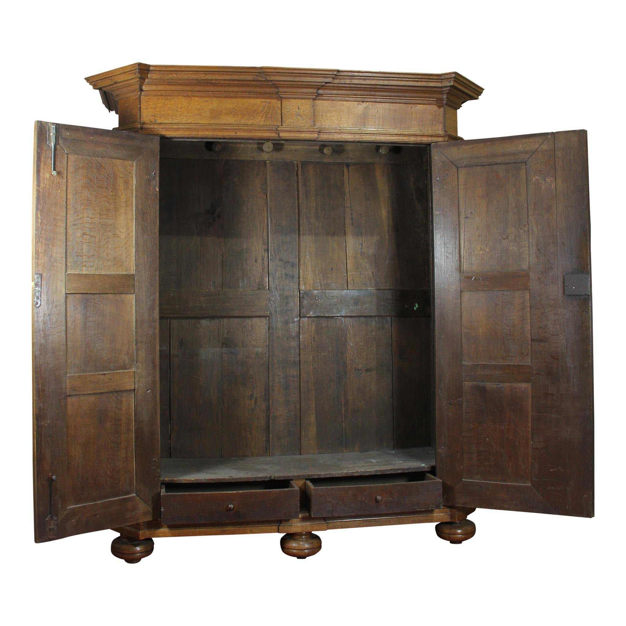 Crafted in Liege, Belgium, the beauty of solid, quarter sawn oak is prominently displayed on the raised panels of the sides and on the doors of this large armoire. Small carvings of pineapple encircled by C scrolls with acanthus leaves adorn the