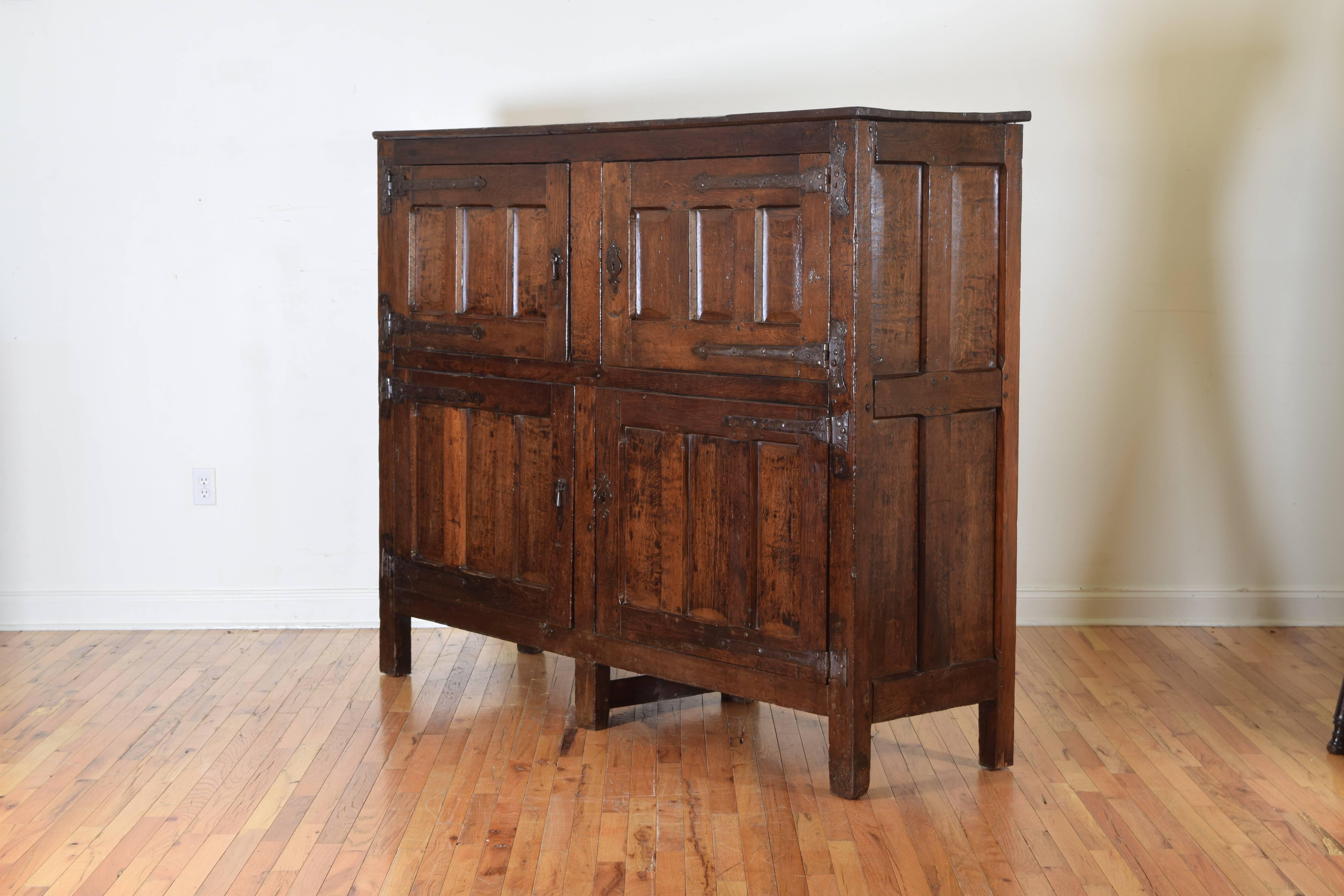 The very solidly built cabinet having two sets of two doors, all paneled, the interiors fitted with recessed shelving, mounted with iron hinges and hardware, working locks.