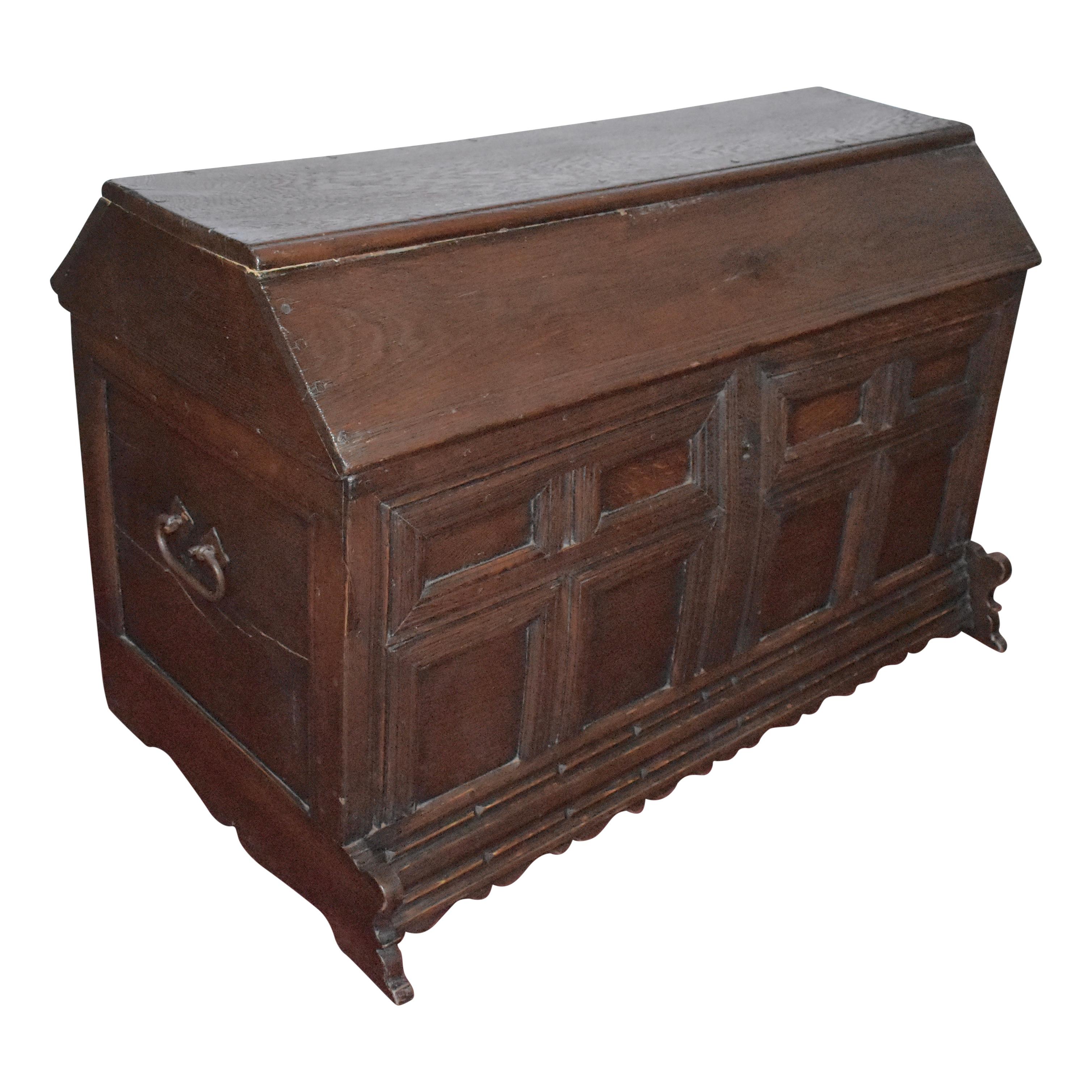 Featuring a dark stain, front recessed panels, and iron loop handles this versatile trunk has generous storage and a unique top, which once served as a saddle stand. Shaped feet and a scalloped front apron add visual interest to the trunk's simple