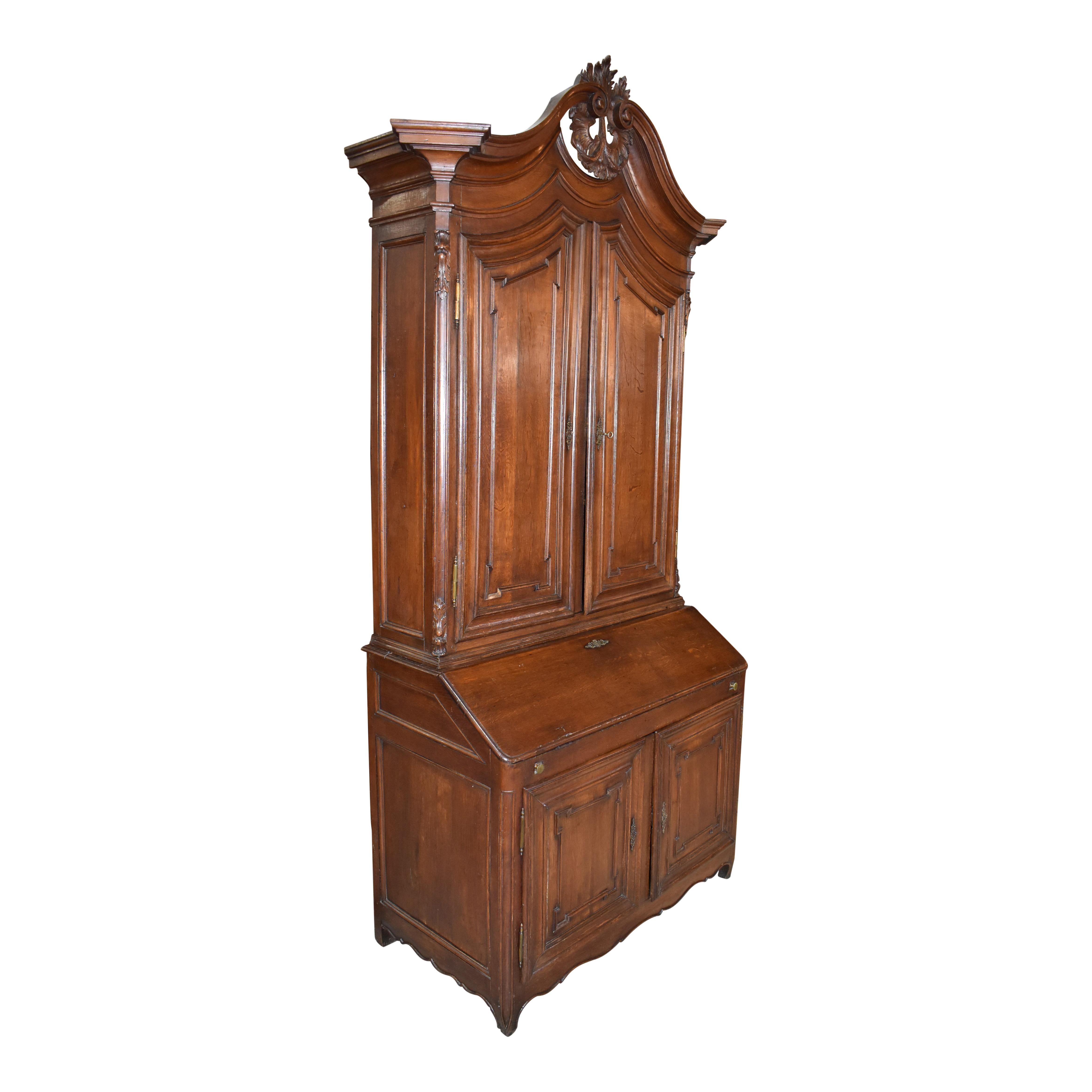 This substantial, mid-19th century secretary features solid oak construction with a beautiful patina. A molded arched cornice with a swan neck pediment crowns the piece and showcases a delicate circular display of fanned leaves to form a stunning