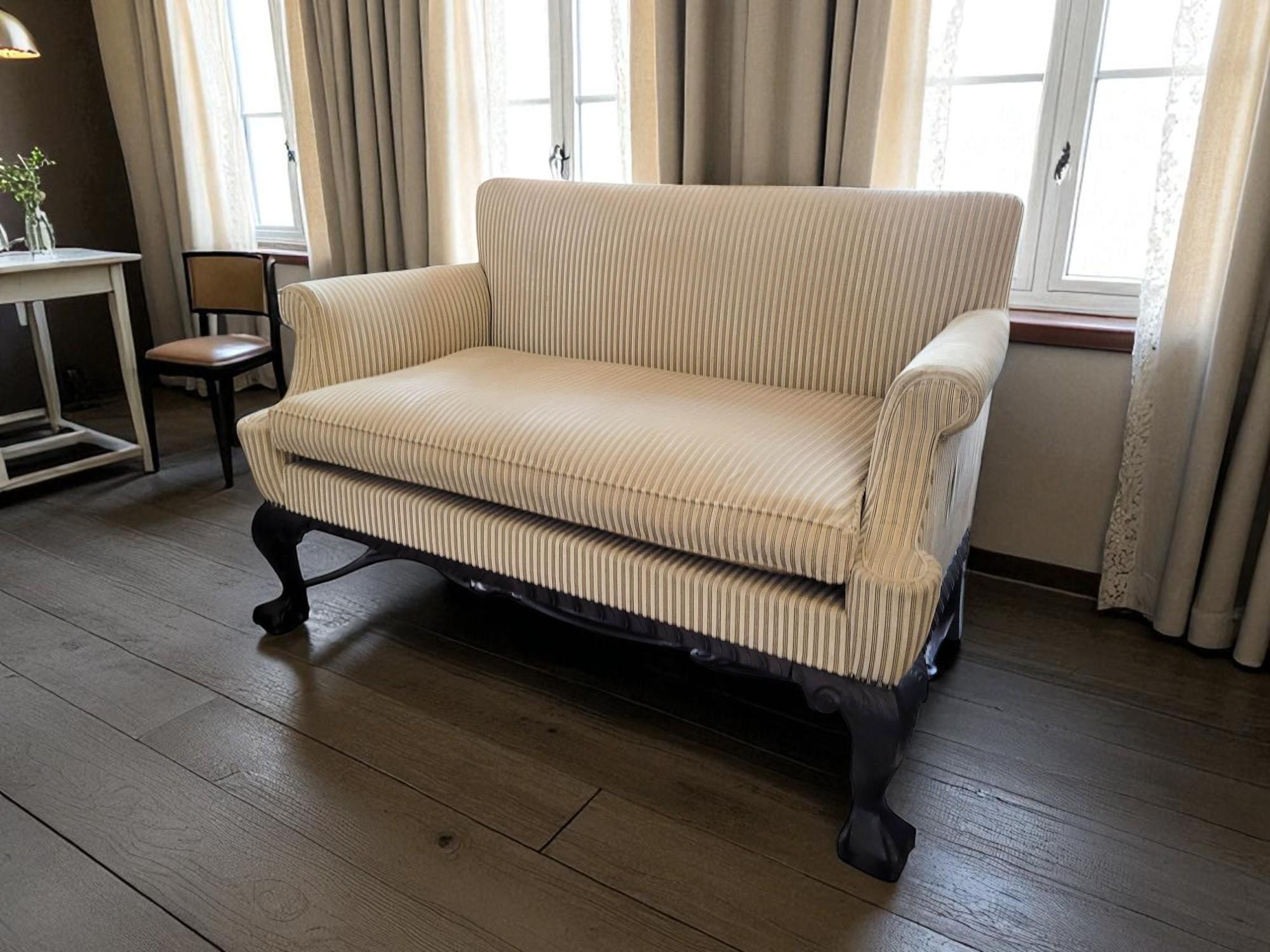 Questo divano unisce l'eleganza del design Queen Anne, Chippendale e Georgiano. Realizzato a mano in Belgio tra la fine del XIX e l'inizio del XX secolo, è un esempio della tradizione nazionale di produzione di mobili pregiati, che fonde influenze
