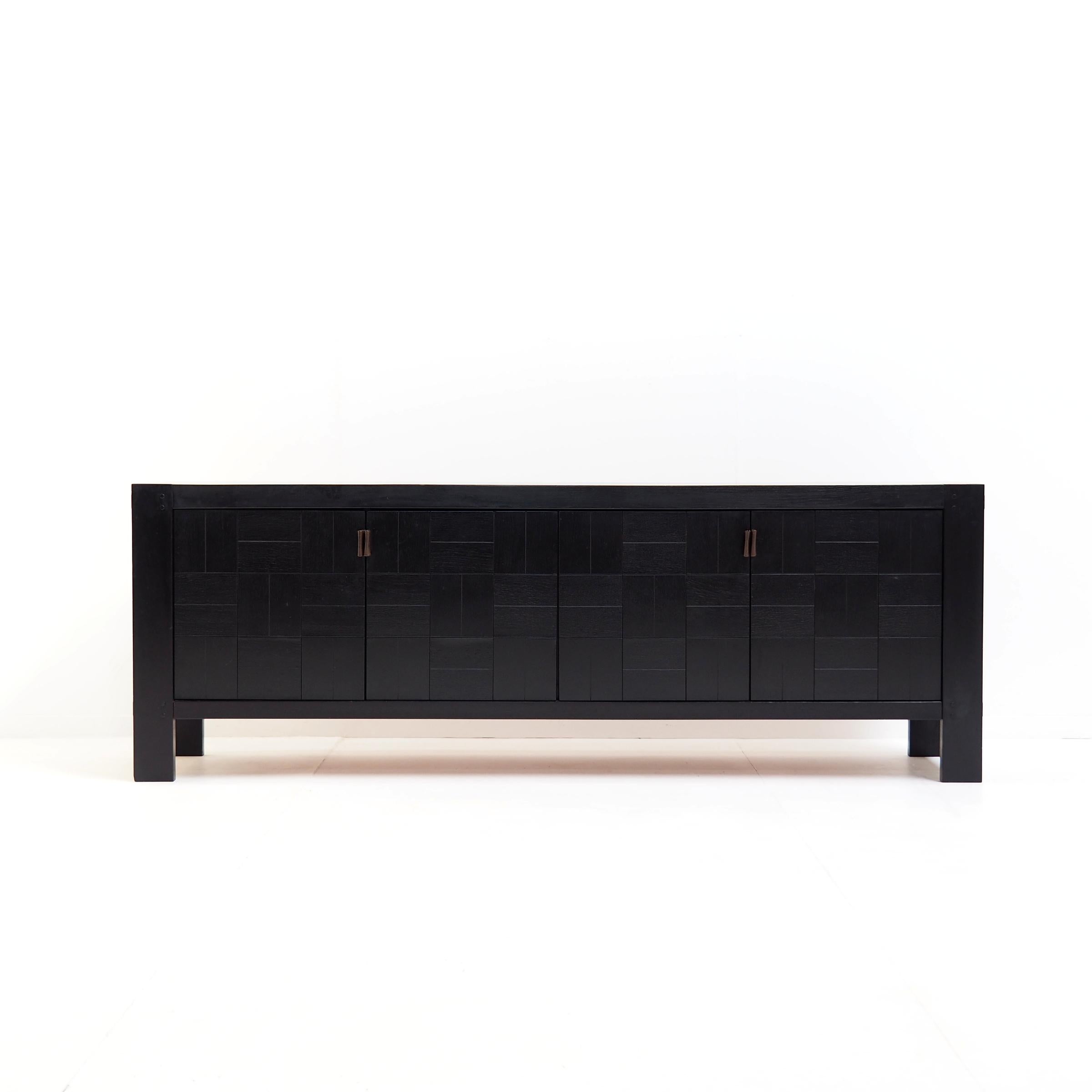 Belgian sideboard in ebonized oak designed in the 1970s by Frans Defour for Defour.

The sideboard is made of a solid oak frame with oak veneer door panels that show a graphic design. The door handles are made of leather, which contrasts very