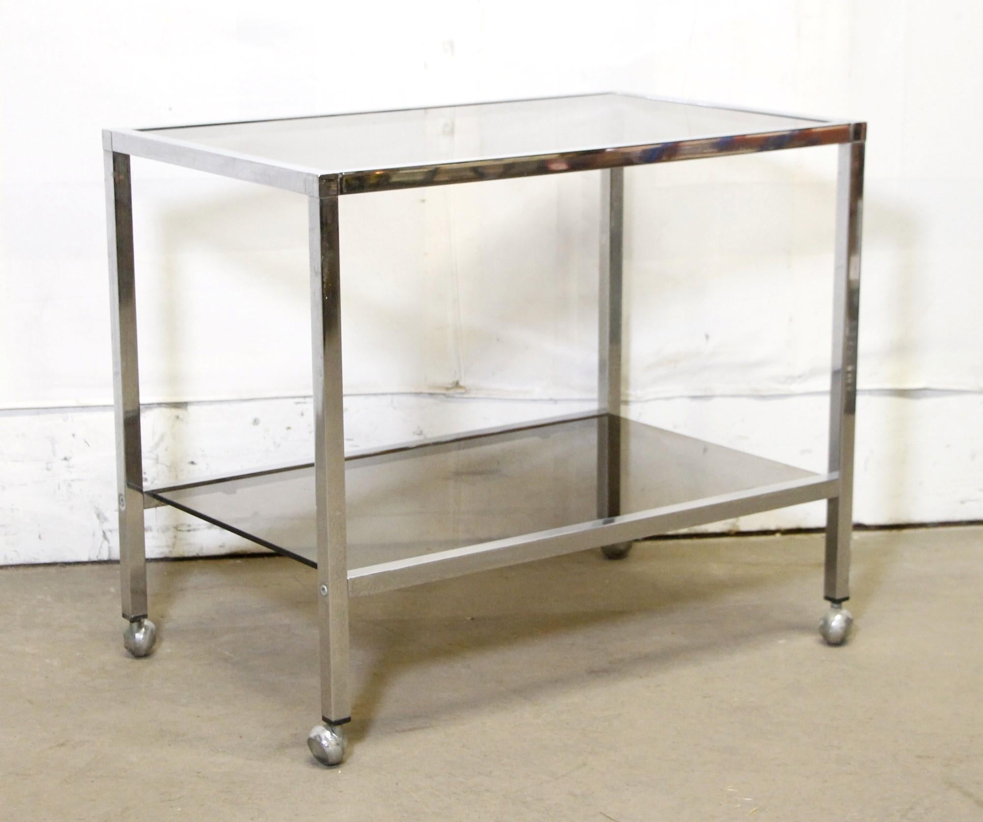 This Mid-Century Modern Belgo Bar Cart was imported from Belgium and features two-tiers with smoked glass shelves. It is chrome plated over steel and has wheels for easy mobility. Please note, this item is located in one of our NYC locations.