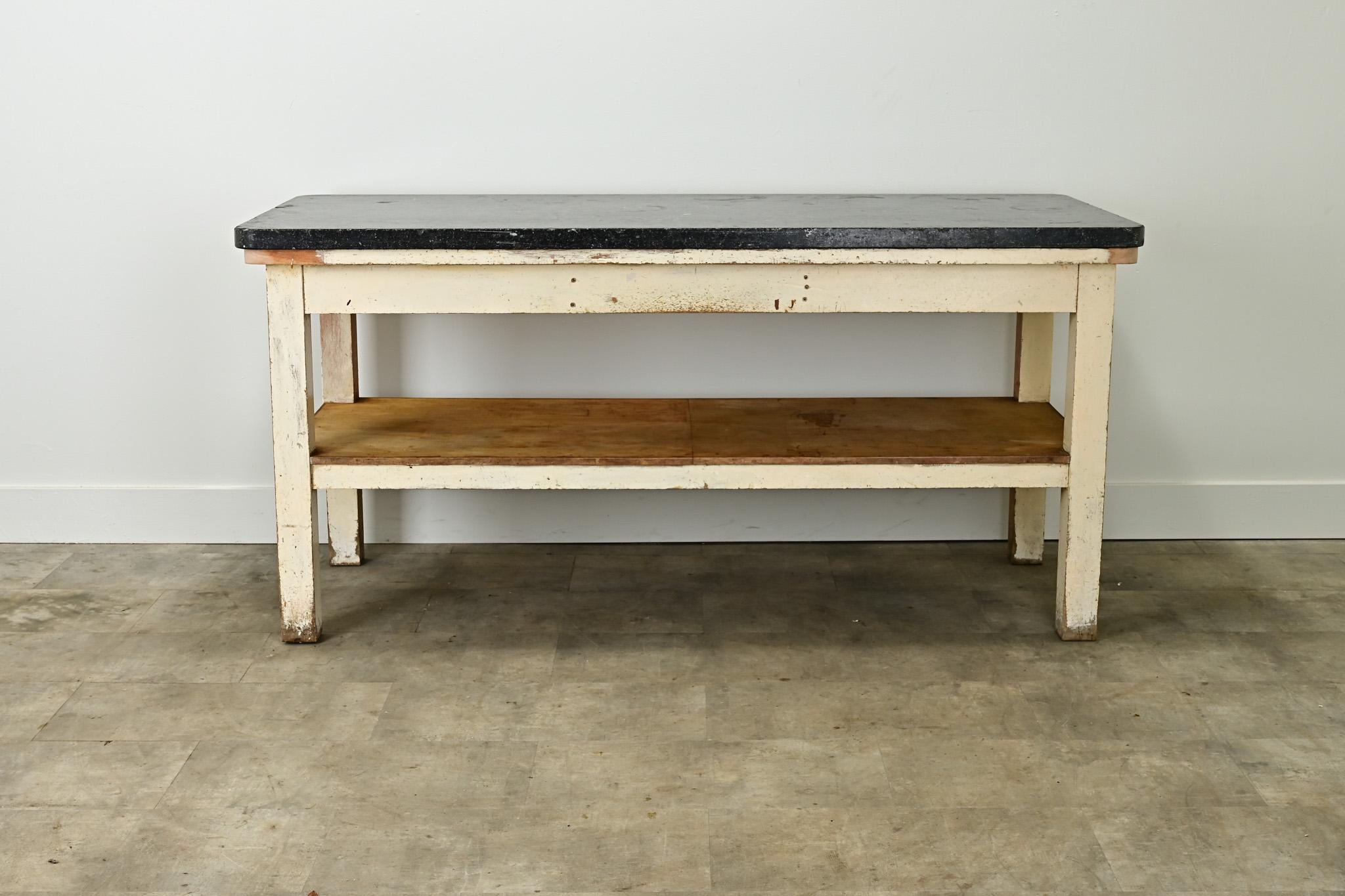 A unique table perfect for a kitchen island. The antique Belgian bluestone slab is 1 ½” thick and is worn with age and patina. The table’s base is made of partially painted pine with four square legs with a storage shelf. It’s likely the stone top