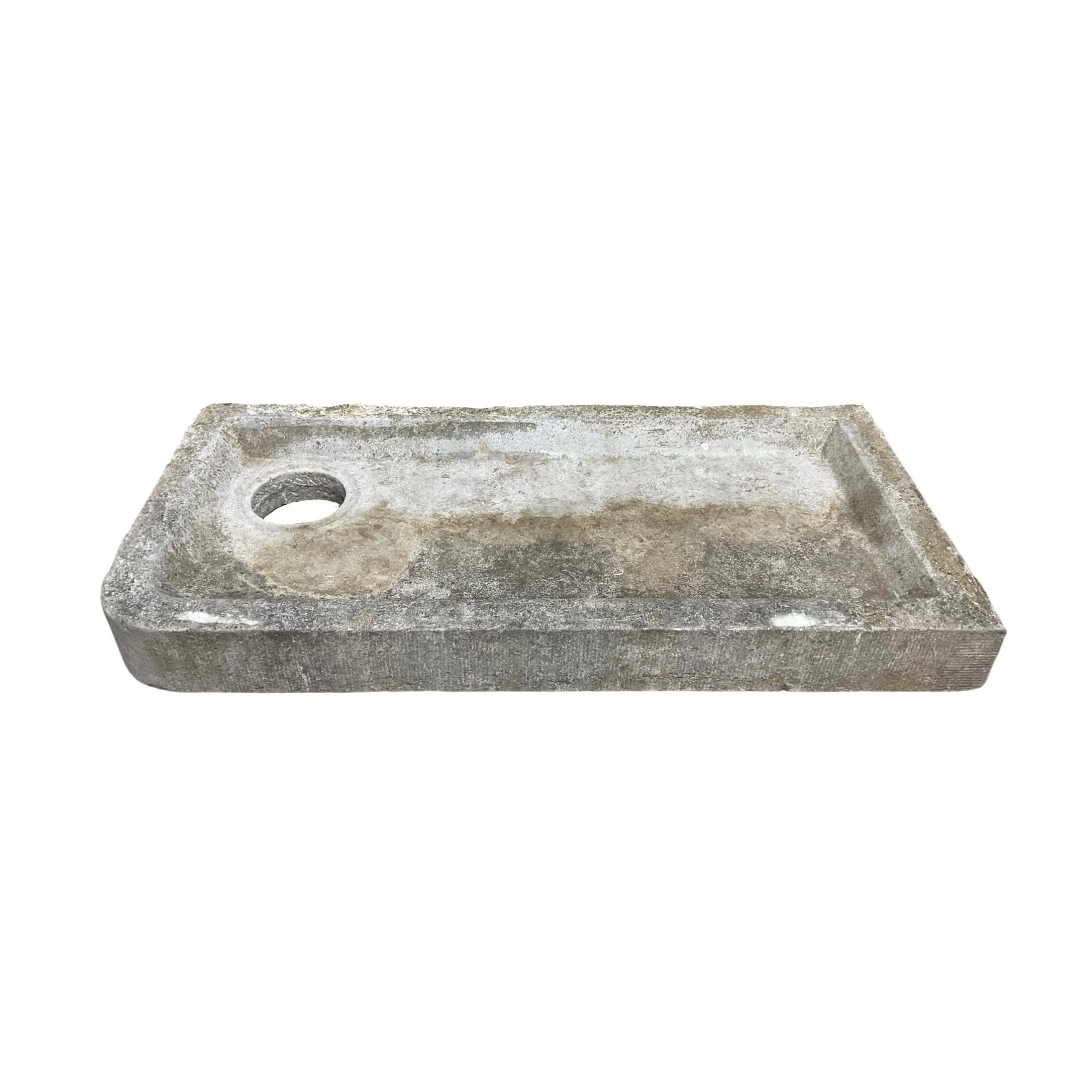 This Belgium Bluestone Sink is a unique piece. Crafted in the 18th century, it has a trough-style design of length and a circle carved for drainage. Its handmade details add an elegant design to any space.