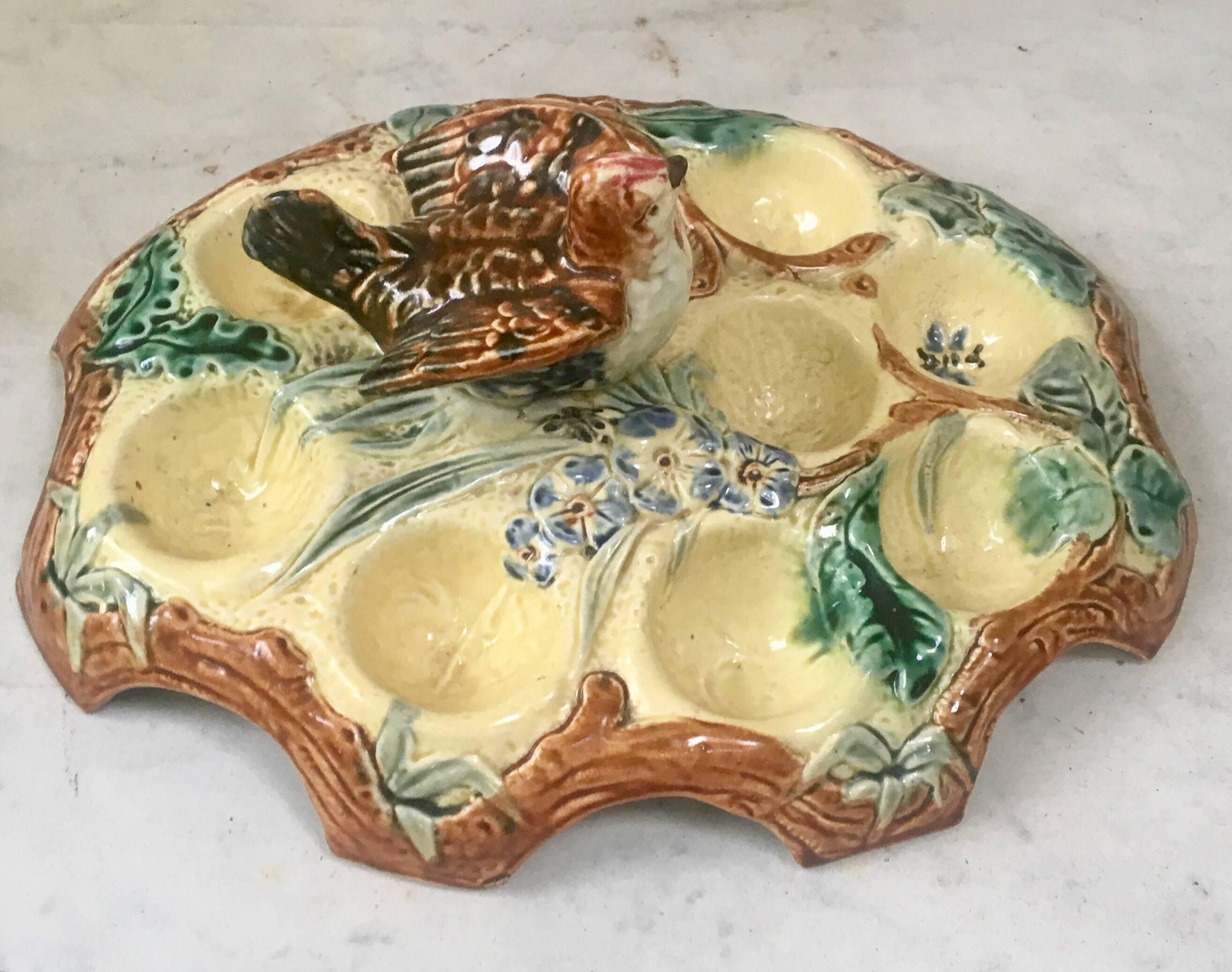 Belgium Majolica egg plate with bird handle for nine eggs decorated with flowers, butterfly and leaves, circa 1880.