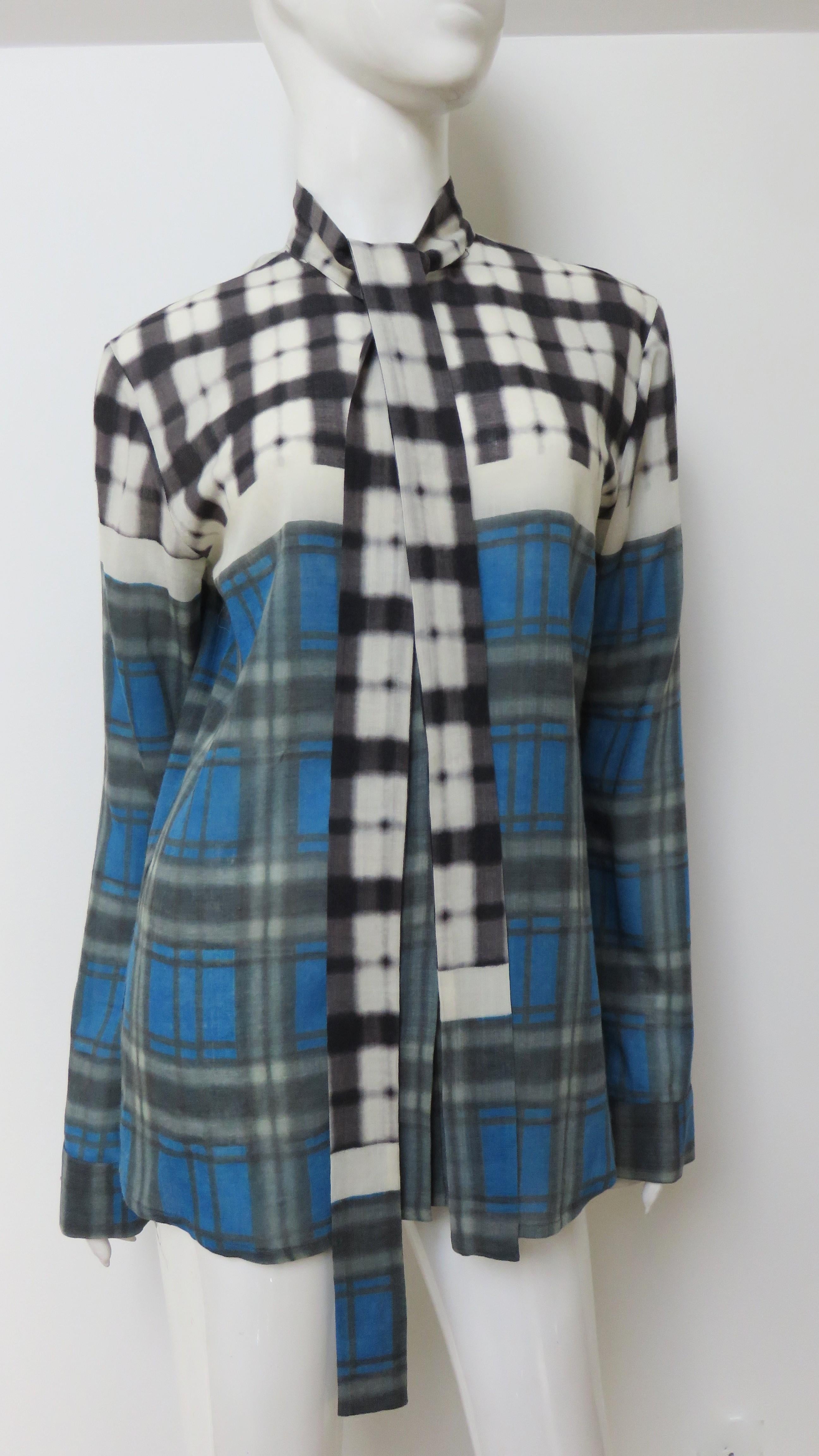 Un grande plaid misto, leggero e morbido.  camicia tessuta in blu, verde nella parte inferiore e grigio, nero e bianco nella parte superiore del petto e delle maniche della stilista belga Mary Katrantzou. Ha maniche lunghe con polsini e bottoni e