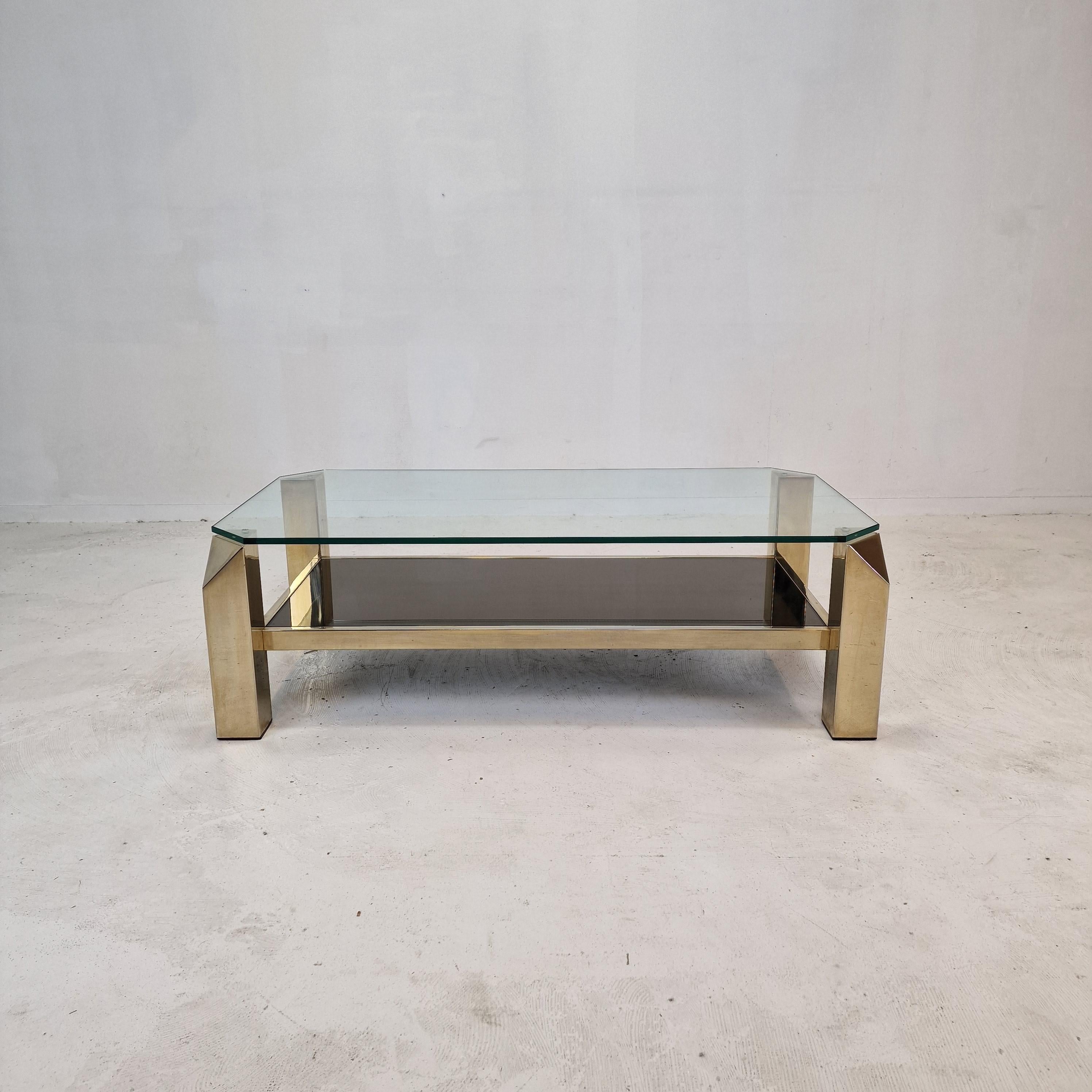 Beautiful coffee table by Belgo Chrom - Dewulf selection, fabricated in the 1970s in Belgium.

A two tier coffee table with a 23kt gold plated base. 
The legs have a geometric design. 

It has the original fumé - smoked mirror glass below and a