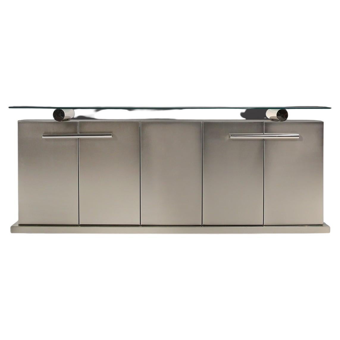 Belgo Chrom credenza in Brushed metal and chrome detailing. A thick floating glass top gives the unit a most royal presence. The four door sideboard is fitted with chrome handles and is in amazing condition. In the style of Maison Jansen. A truly