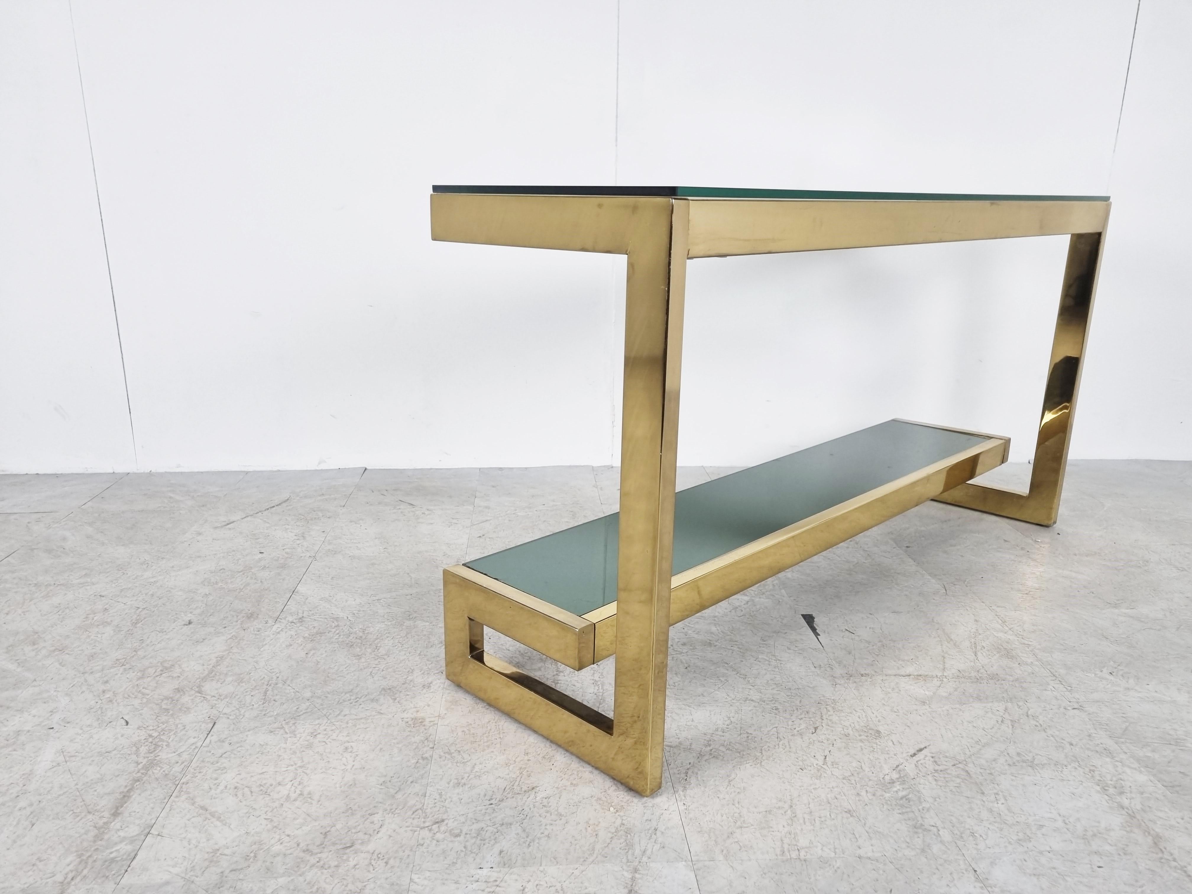23kt gold layered 'G'-shaped console table produced by Belgochrom.

The table has mirrored and clear glass tops

Original condition with some wear on the brass, condition as picture. The glass is in good condition. Over the item look very