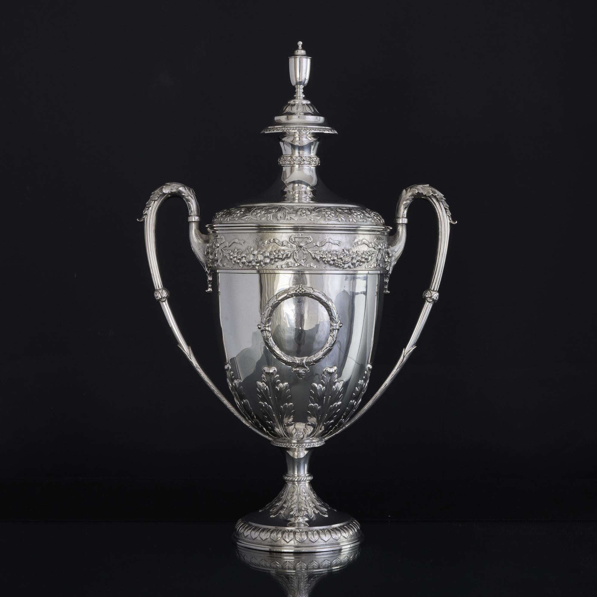 Impressive, large handmade silver trophy cup and cover decorated with raised hand chased sections of acanthus leaves, a panel of fruit and berry garlands with ribbon ties around the rim of the cup. The cover features a panel of swirling foliage
